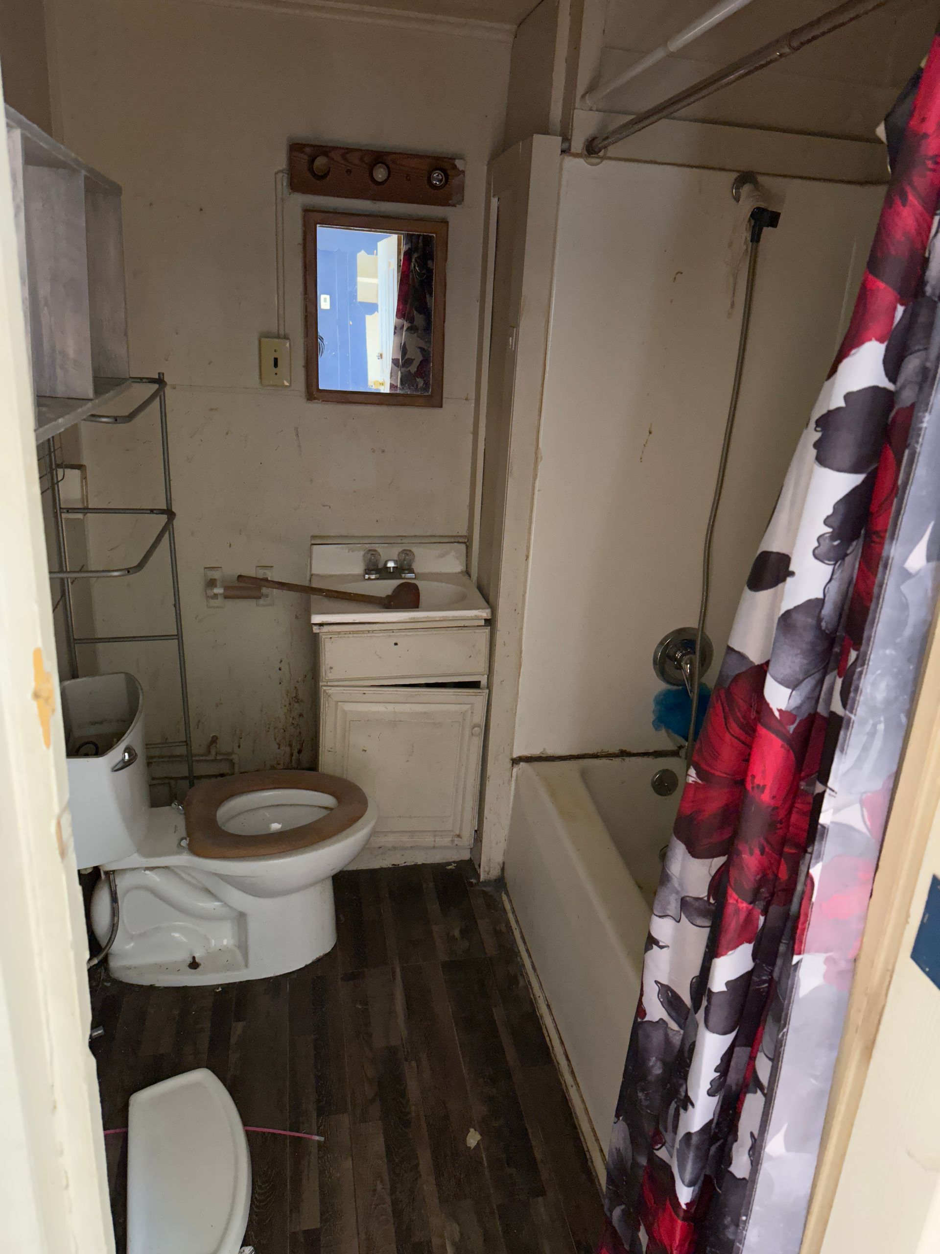 Bathroom with a toilet, sink, tub, and shower curtain.