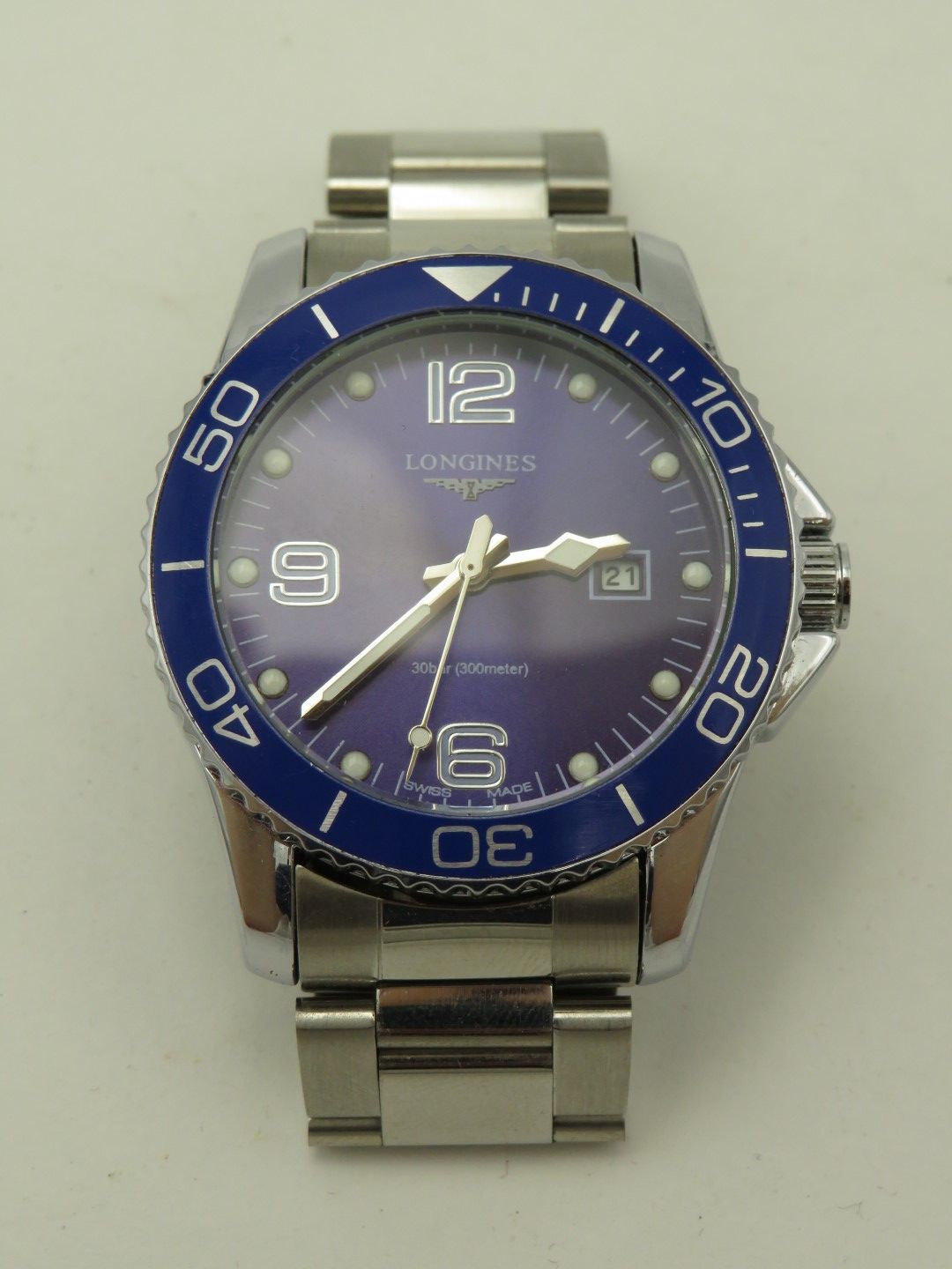 Stainless steel Longines watch with a blue bezel and purple dial.