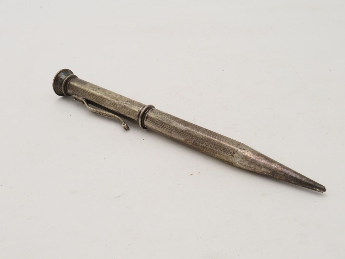 Silver pencil on a white background, featuring a clip and a tapered tip.