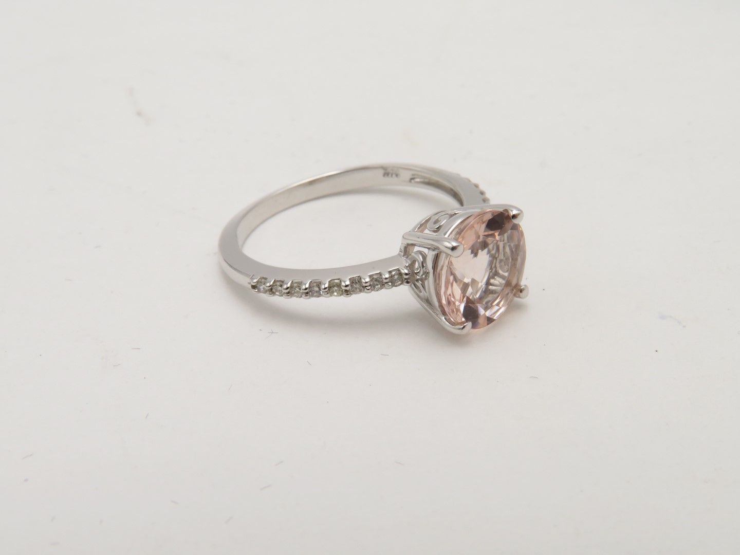Silver ring with a large pink oval gemstone and small diamonds along the band.