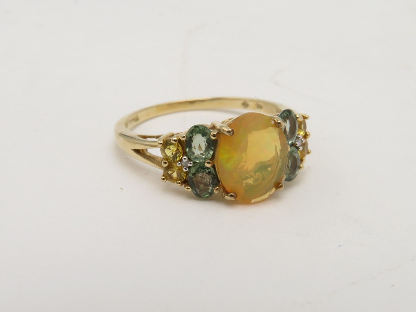 Gold ring with a large oval, orange gemstone and smaller surrounding colorful gems.