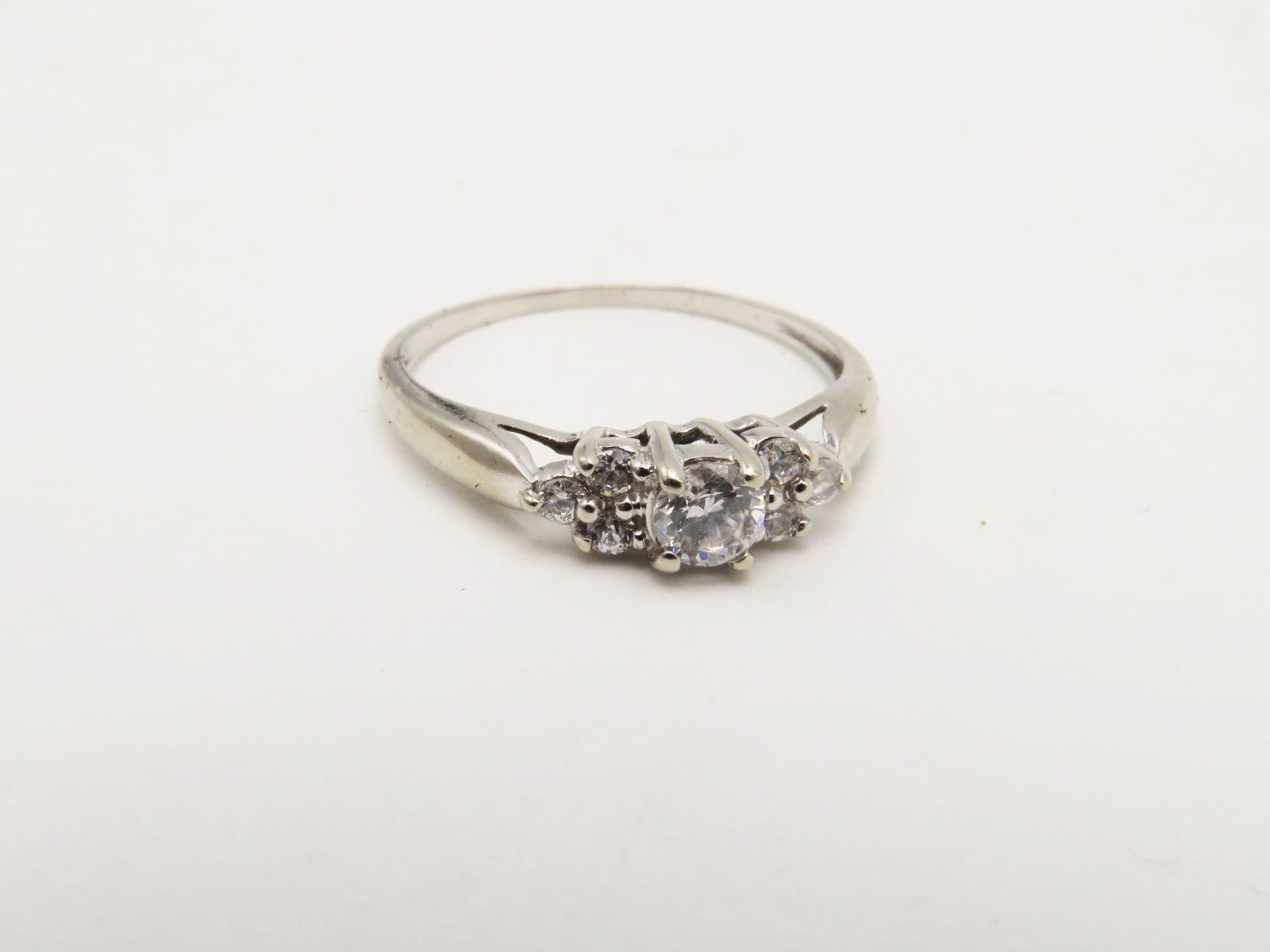 Silver ring with a large center stone and smaller side stones, set against a white background.