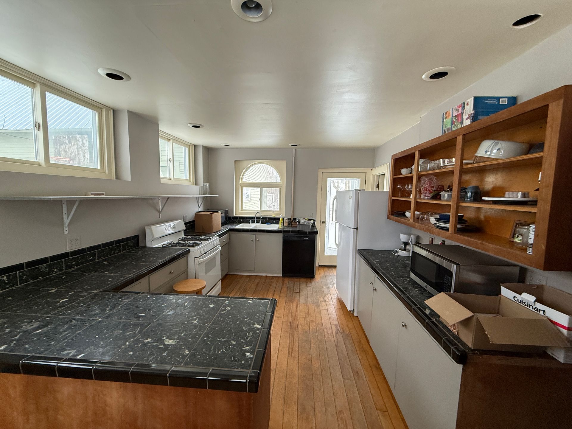Kitchen with a U-shaped countertop, wooden cabinets, and a white refrigerator; gray walls and a window.