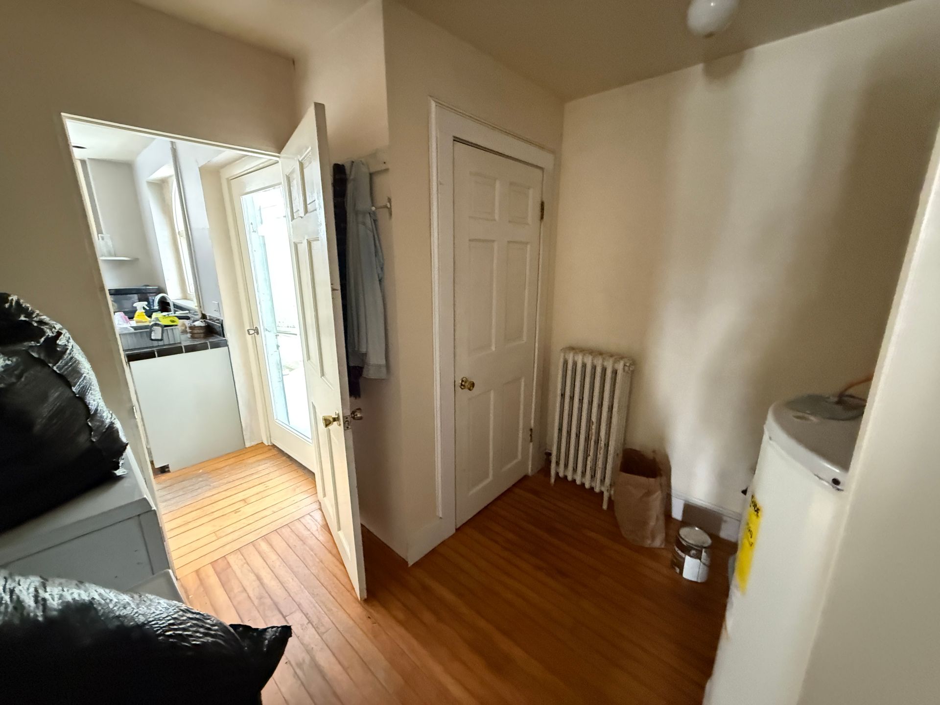 Hallway with doors, radiator, and water heater. Sunlight streams into the hallway.