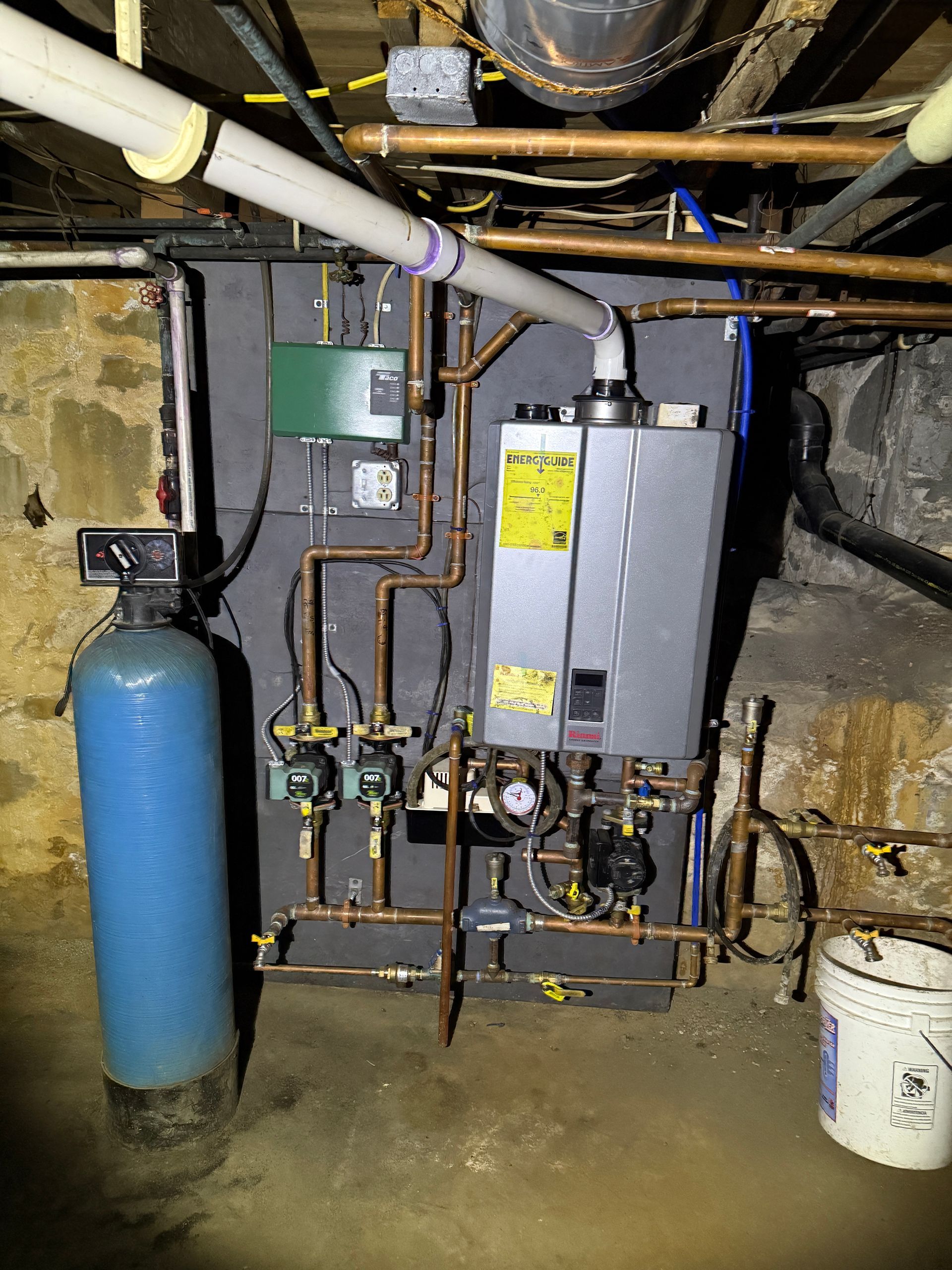 Plumbing system in a basement with water heater, water softener, and copper pipes.