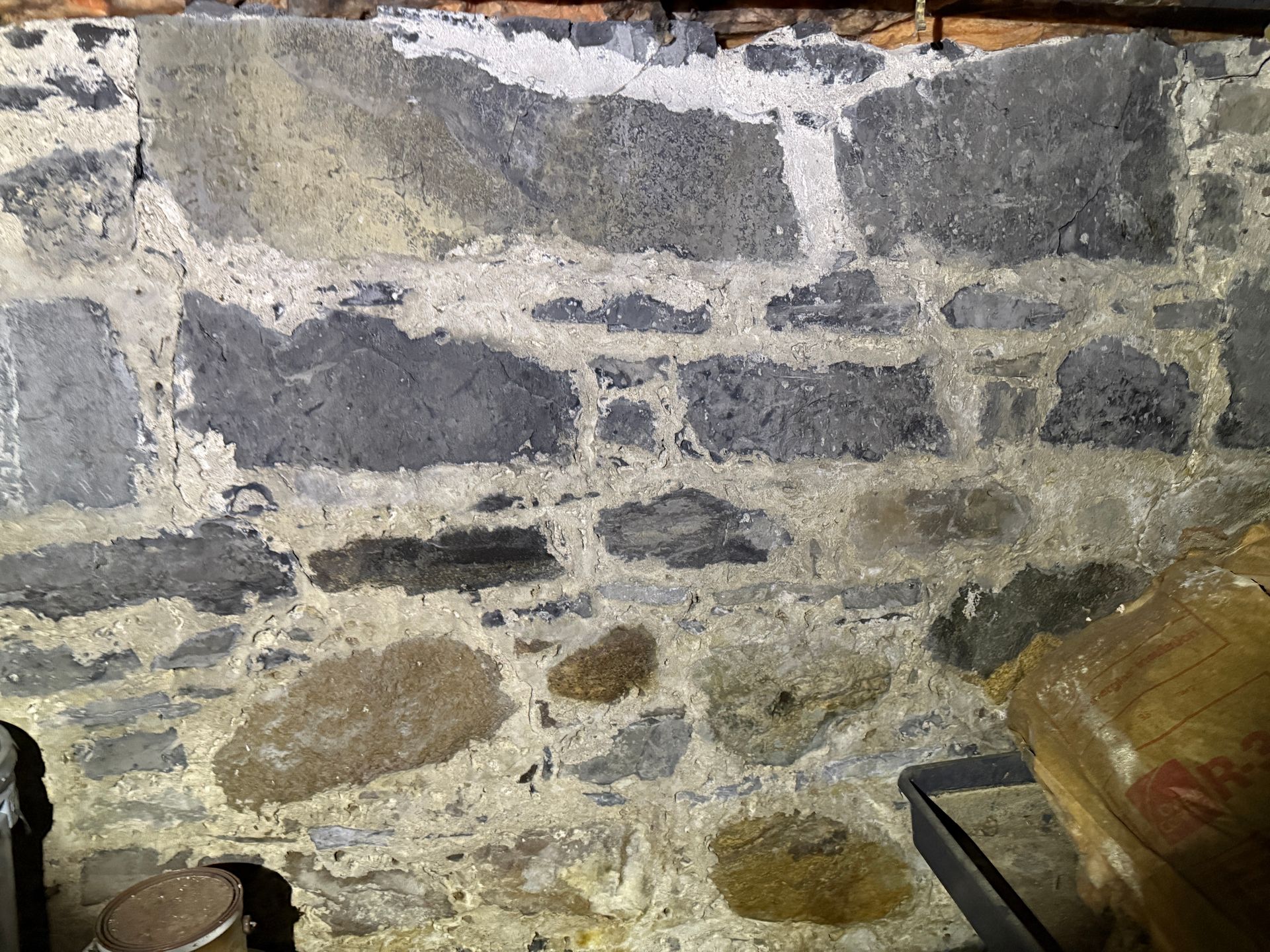 Stone wall with gray and tan stones, mortared with light gray.