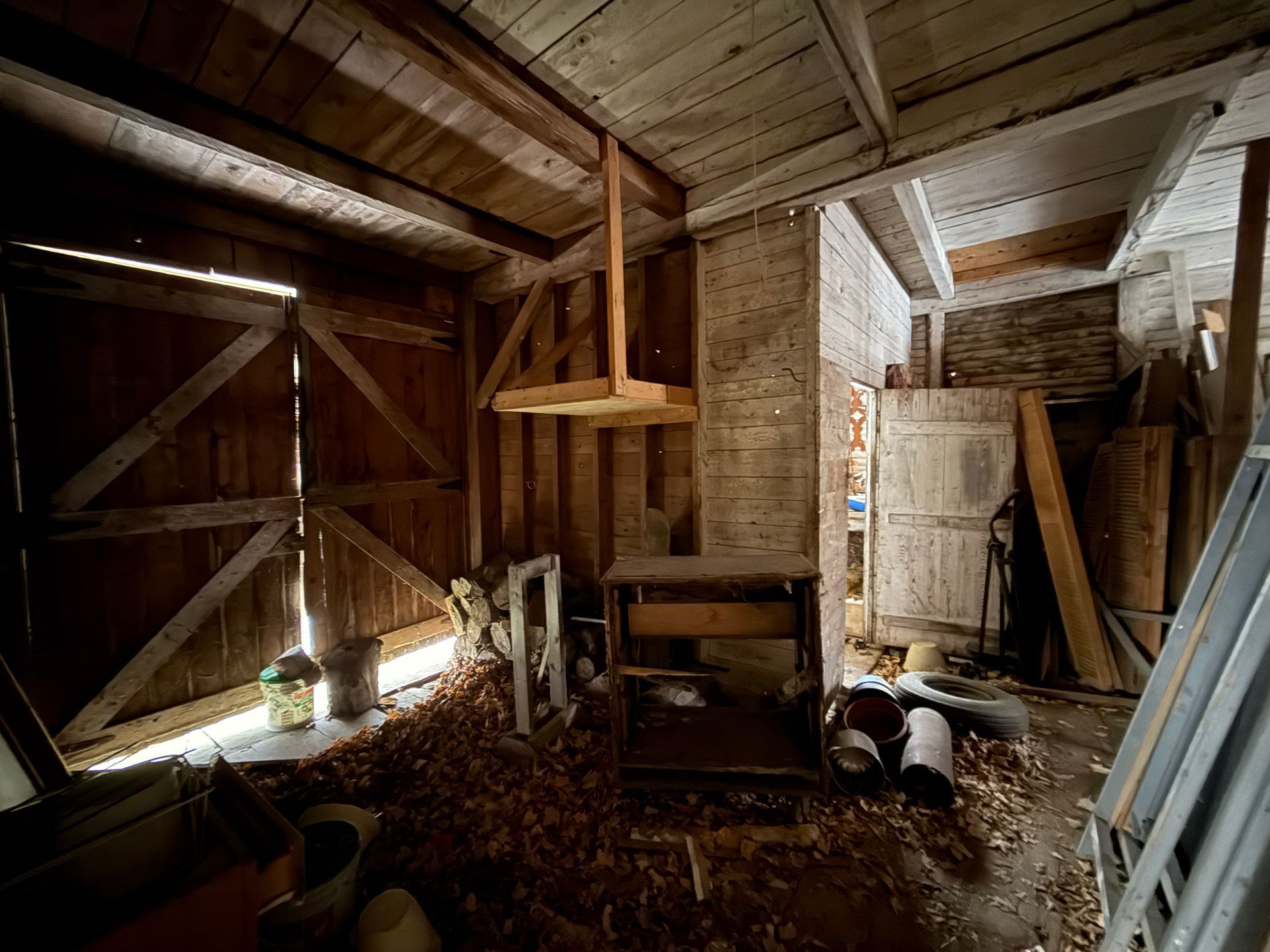 Interior of a rustic, wooden shed with sunlight streaming in.