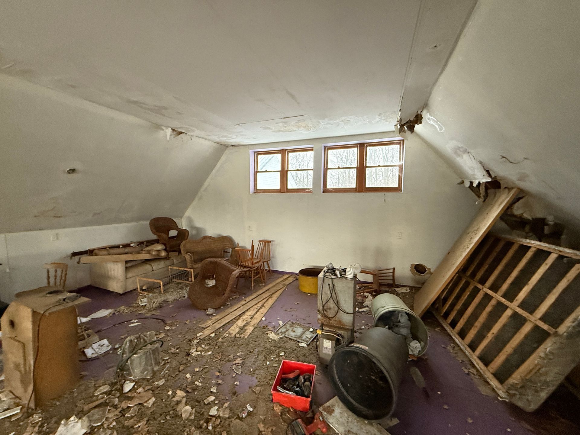Attic room with furniture, and a small window.