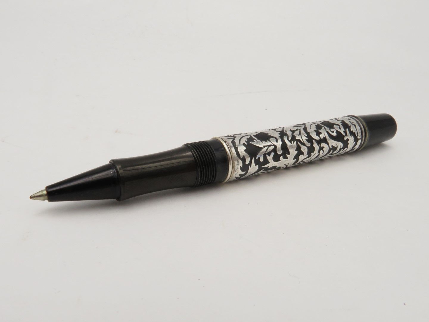 Black and silver rollerball pen with intricate design.