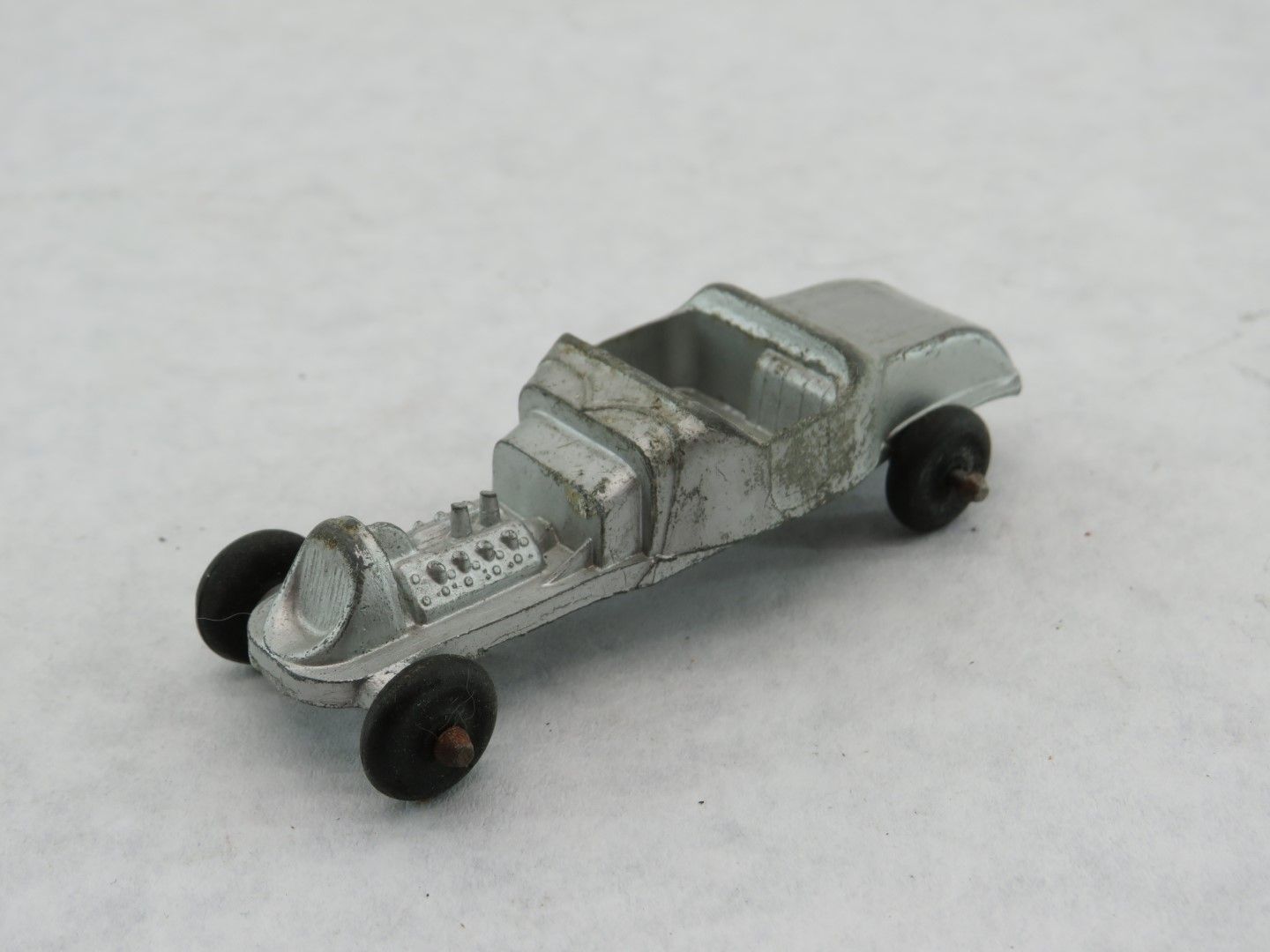 Silver die-cast toy car with black wheels, possibly vintage or antique. Antique.