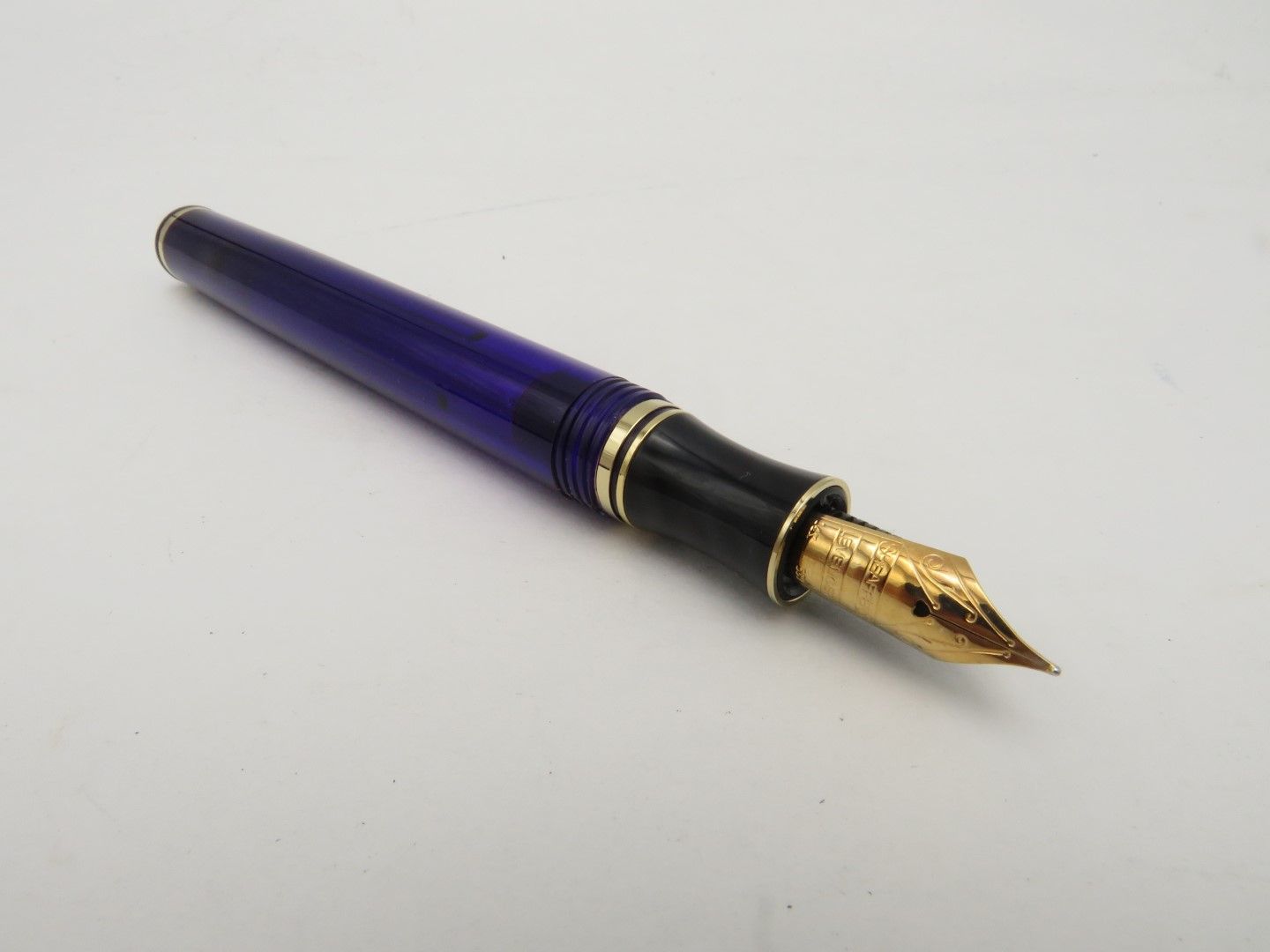 Blue and black fountain pen with a gold nib on a white surface.
