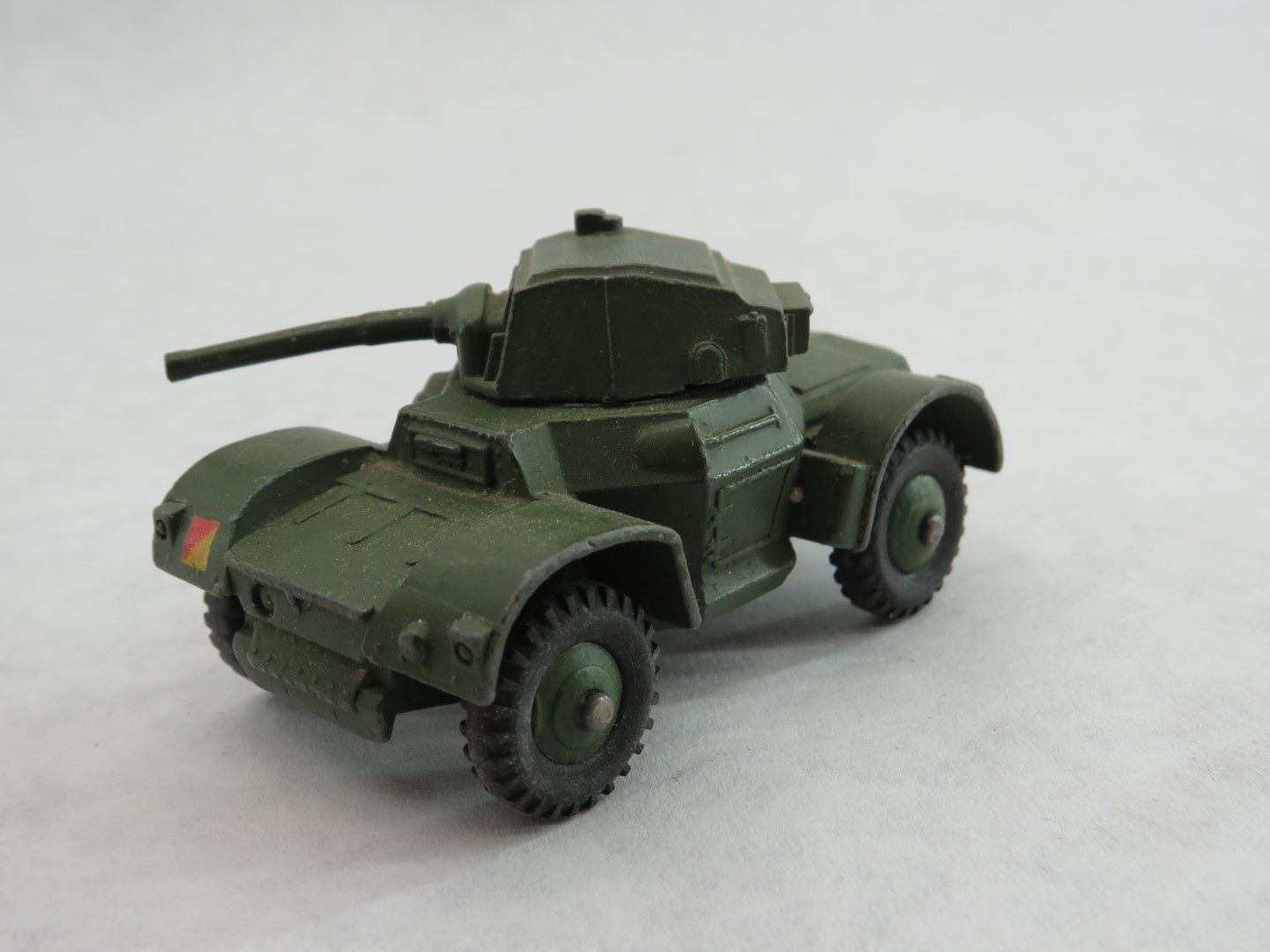 Green toy armored car with a turret, on a white surface. Antique.