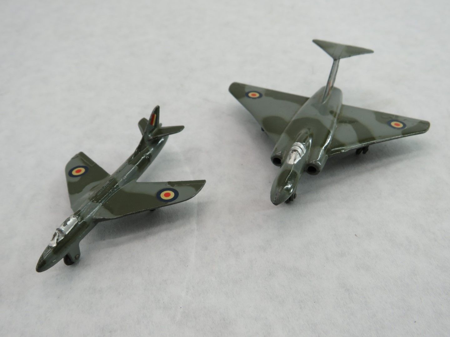 Two toy Hawker Hunter fighter jets with camouflage paint, on a light surface. Antique.