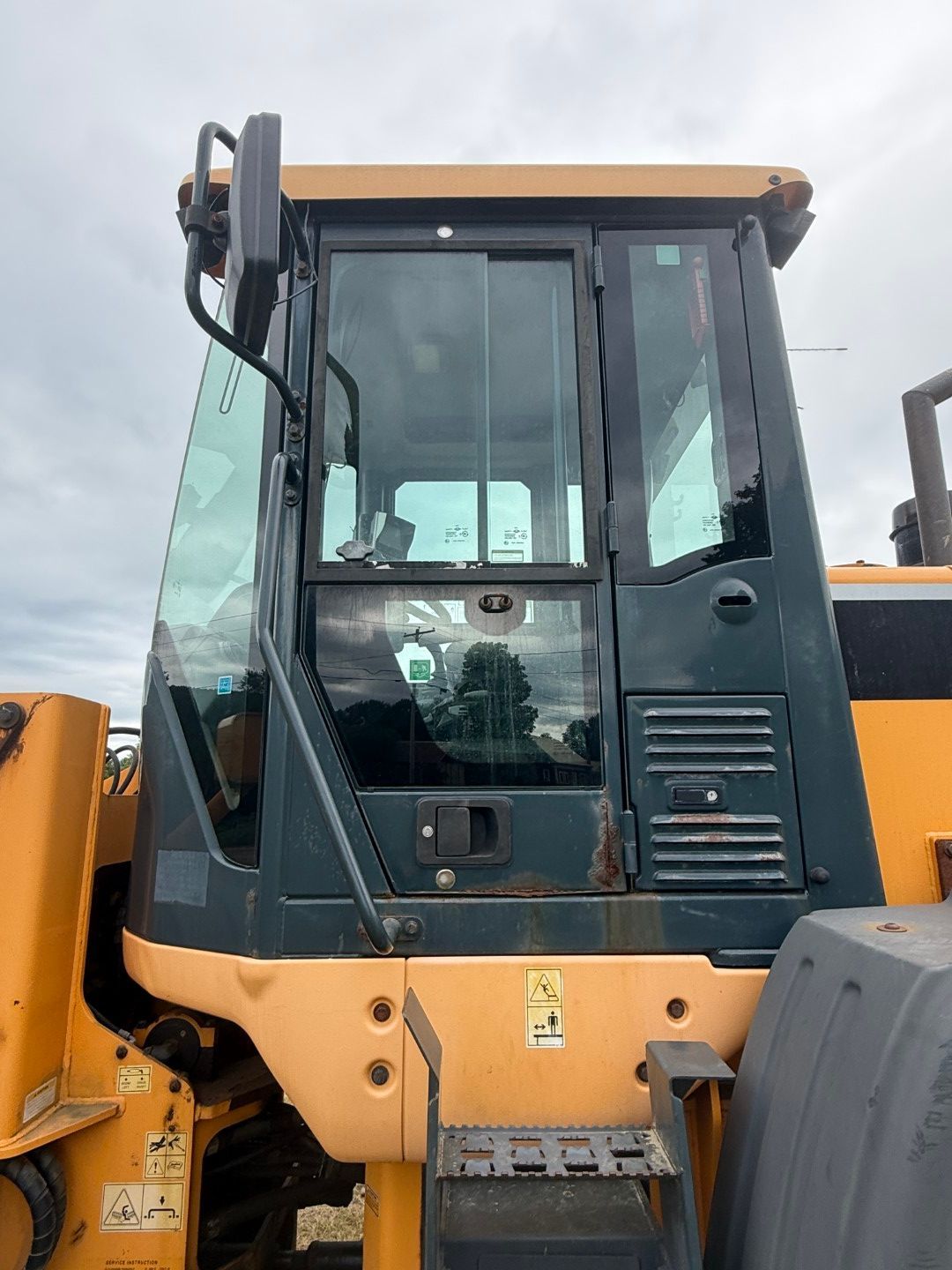 Yellow and dark blue construction vehicle cab with tinted windows and a side mirror