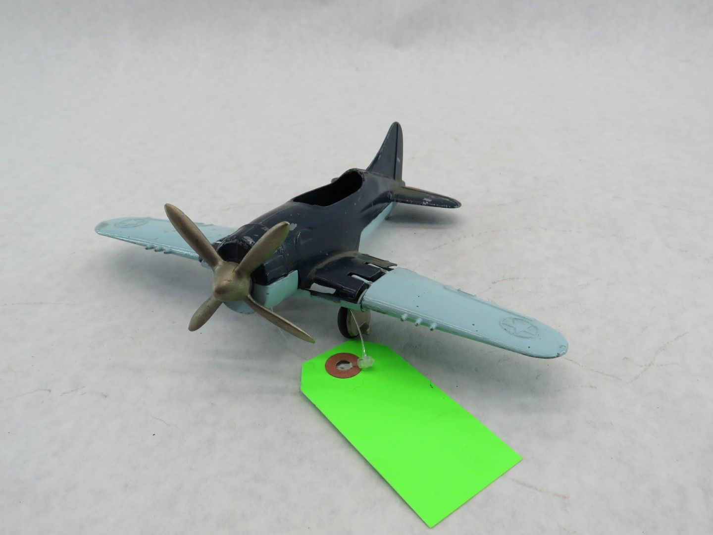 Toy airplane with a blue body, light blue wings, and a brass propeller. Antique.