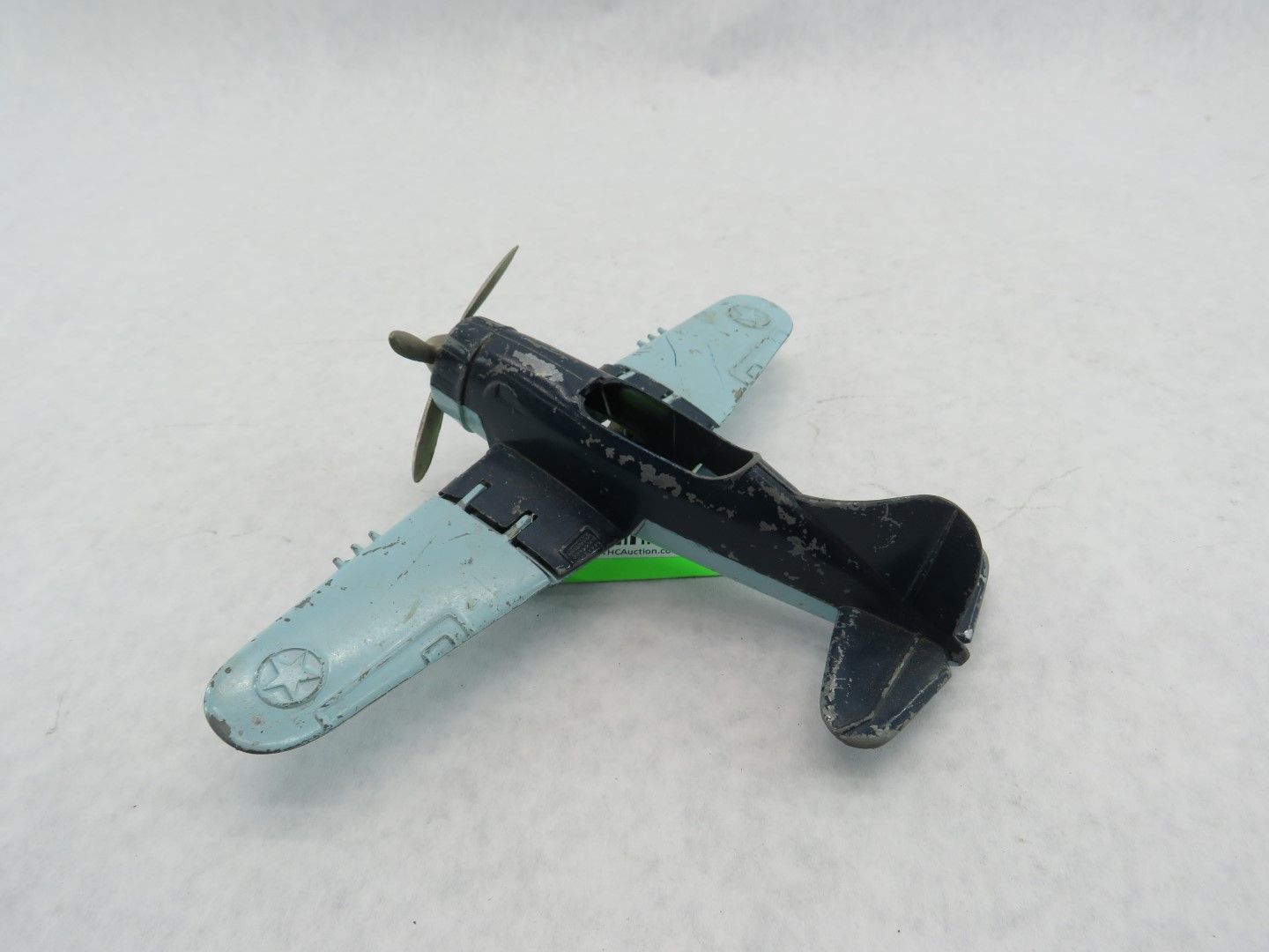 Toy airplane, dark blue body, light blue wings, propeller, white background. Antique.