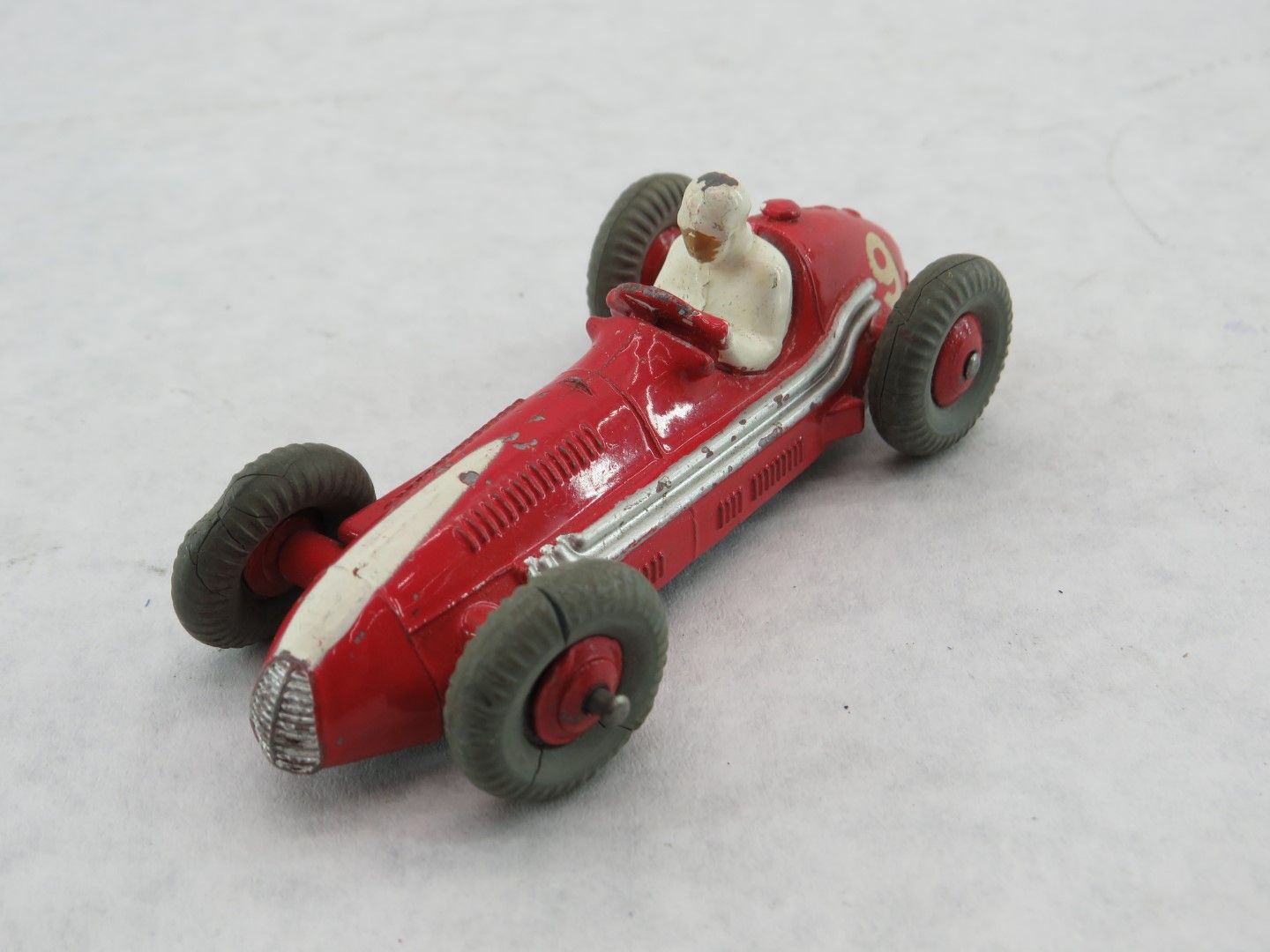 Red and white toy race car with gray tires and a driver. Antique.