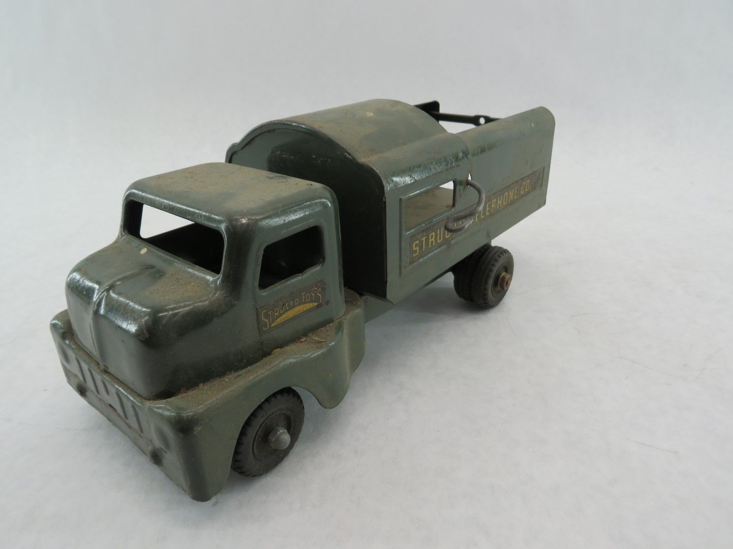 Green vintage toy truck with a raised cargo bed.