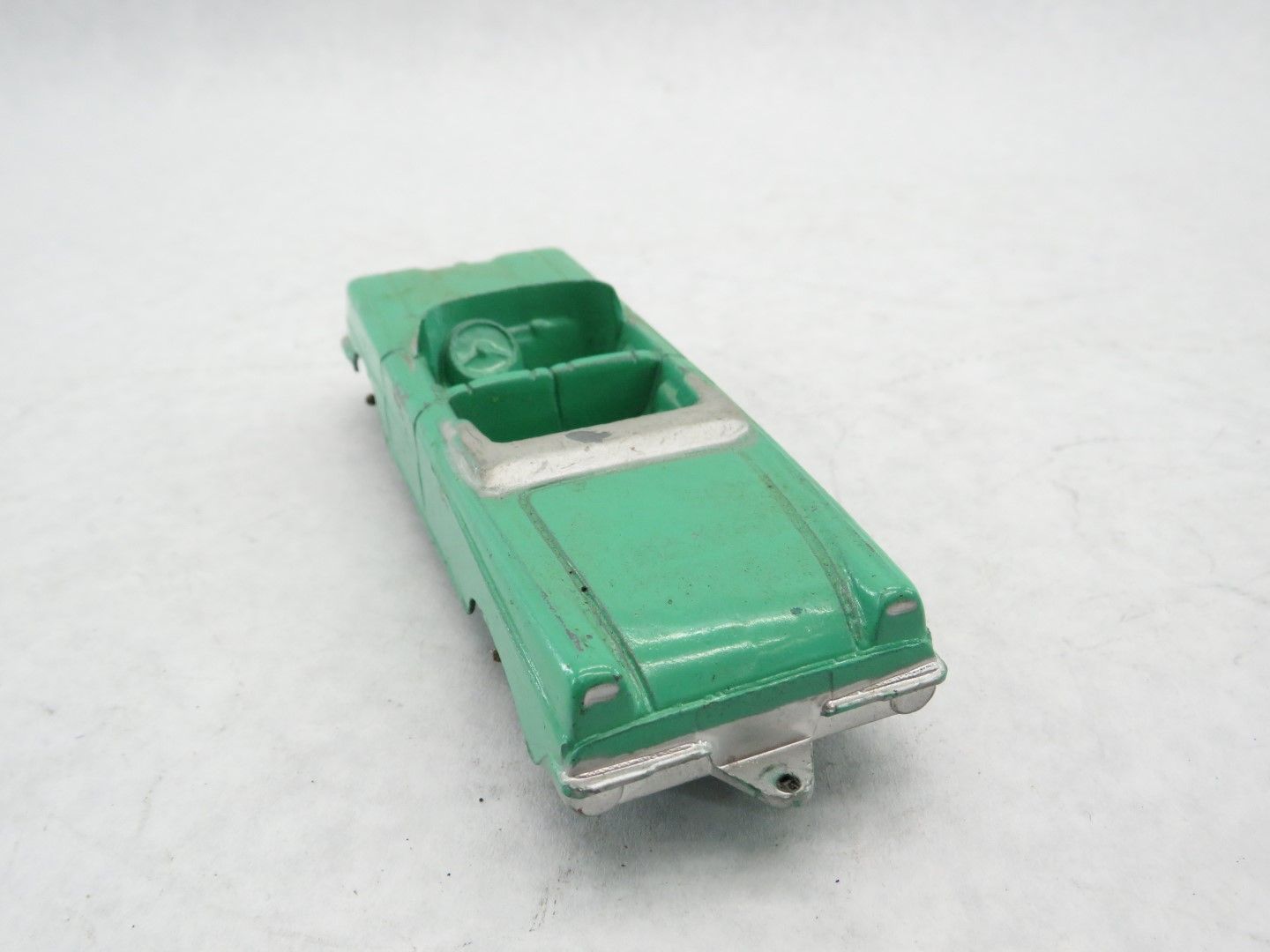 Green toy convertible car on a white surface. Antique.