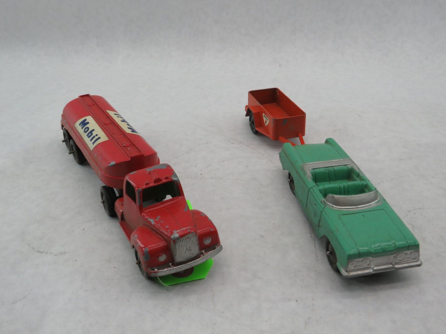 Red Mobil tanker truck and green convertible toy cars. Red trailer attached to green car. Antique.