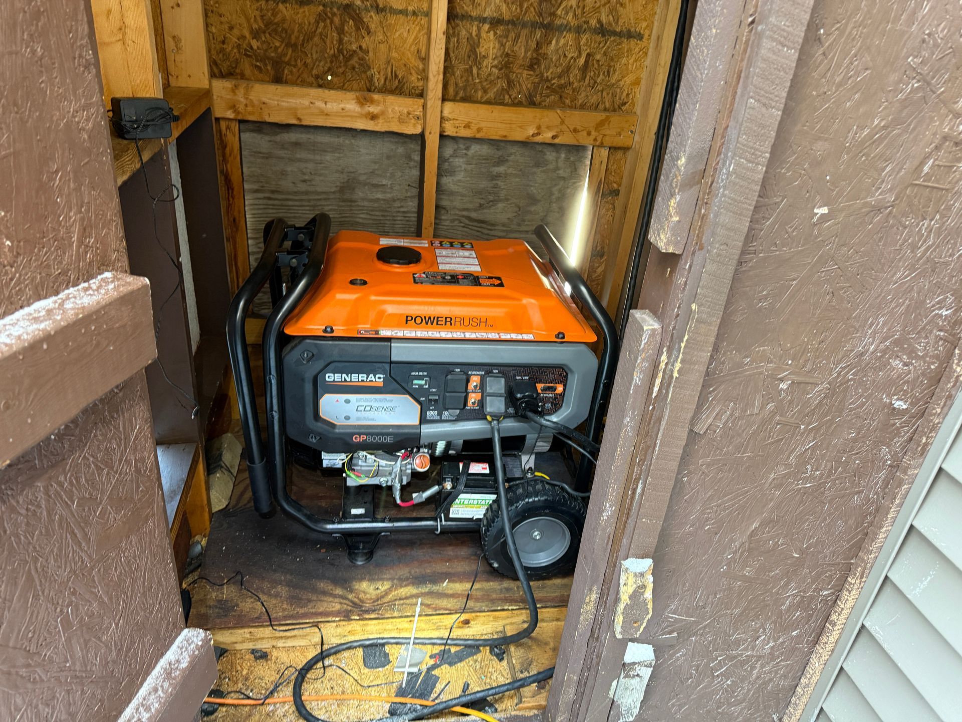 Orange generator inside a wooden shed.
