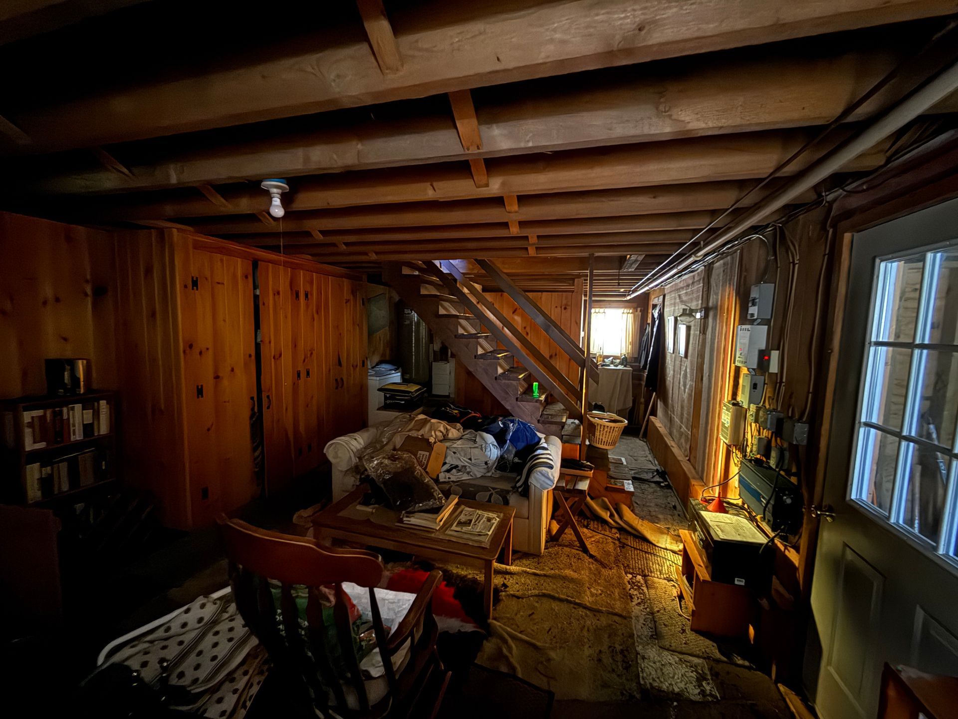 Basement with wooden walls and a staircase leading upwards.