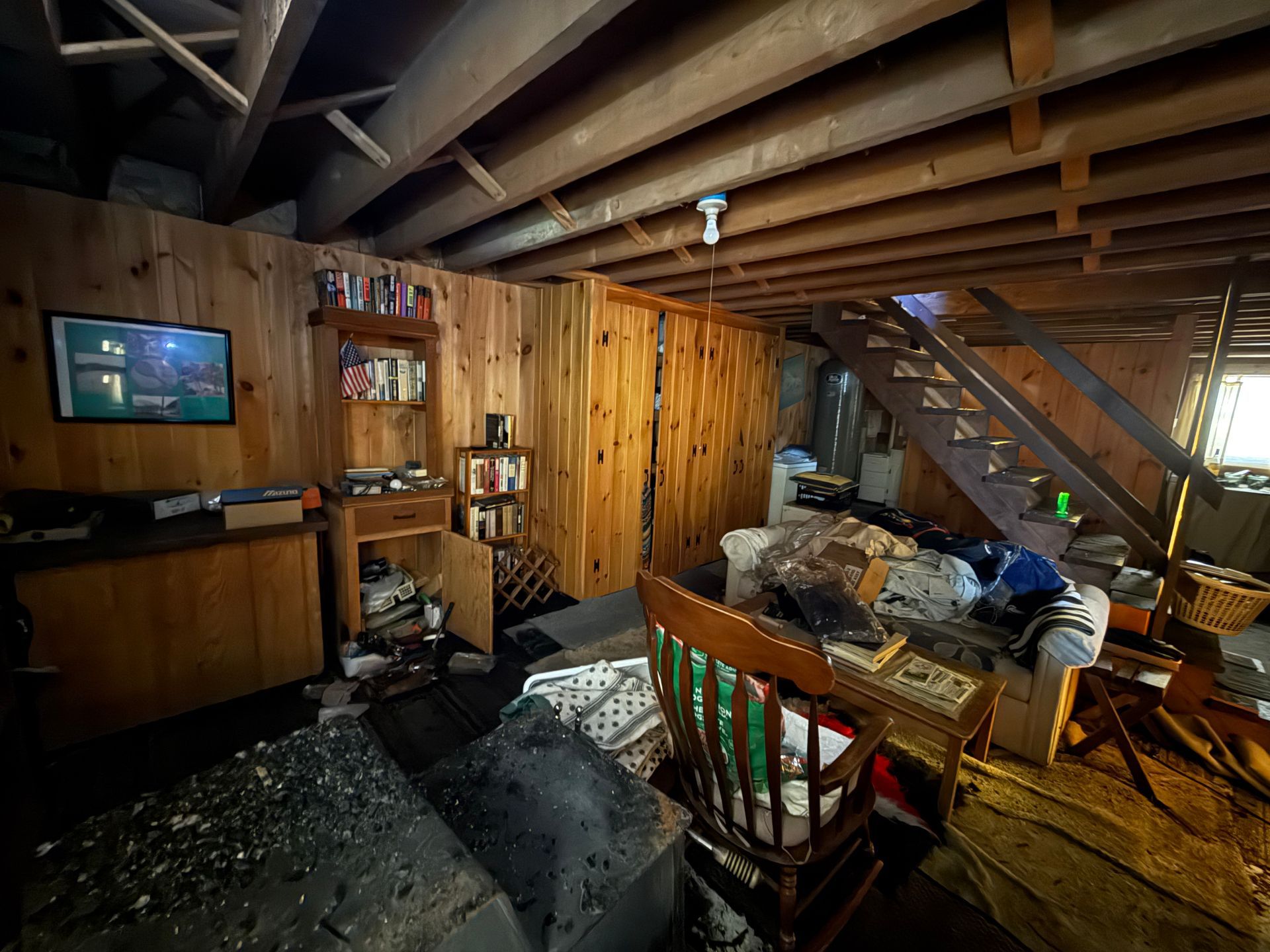 Basement interior with wood paneling, furniture, and a staircase.