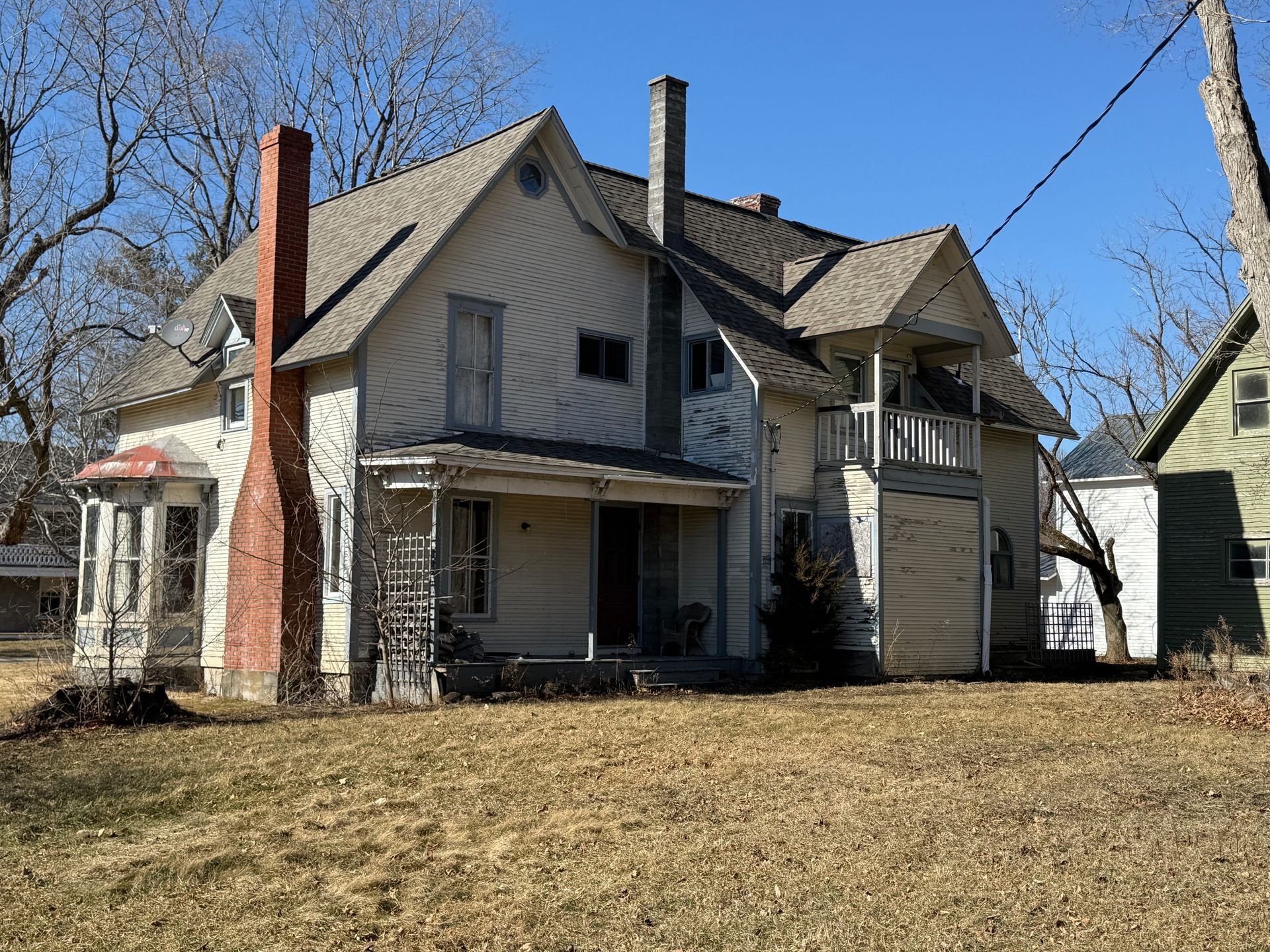 Two-story house with a prominent red brick chimney and a small porch.