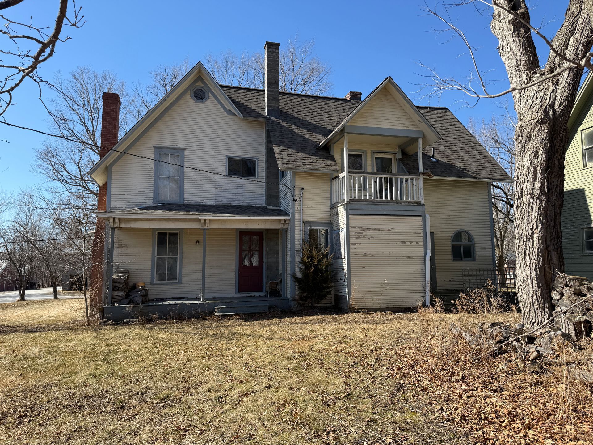 Two-story house with a porch and balcony; brown roof; on a sunny day.