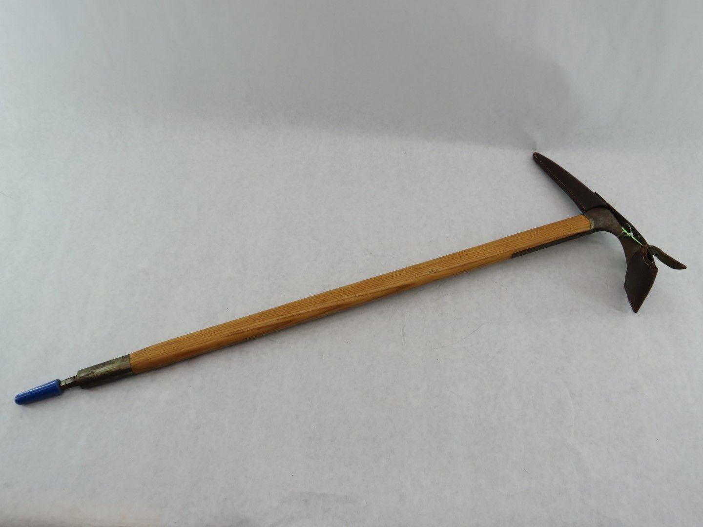 Pickaxe with a wooden handle and blue tip against a white background. Antique.