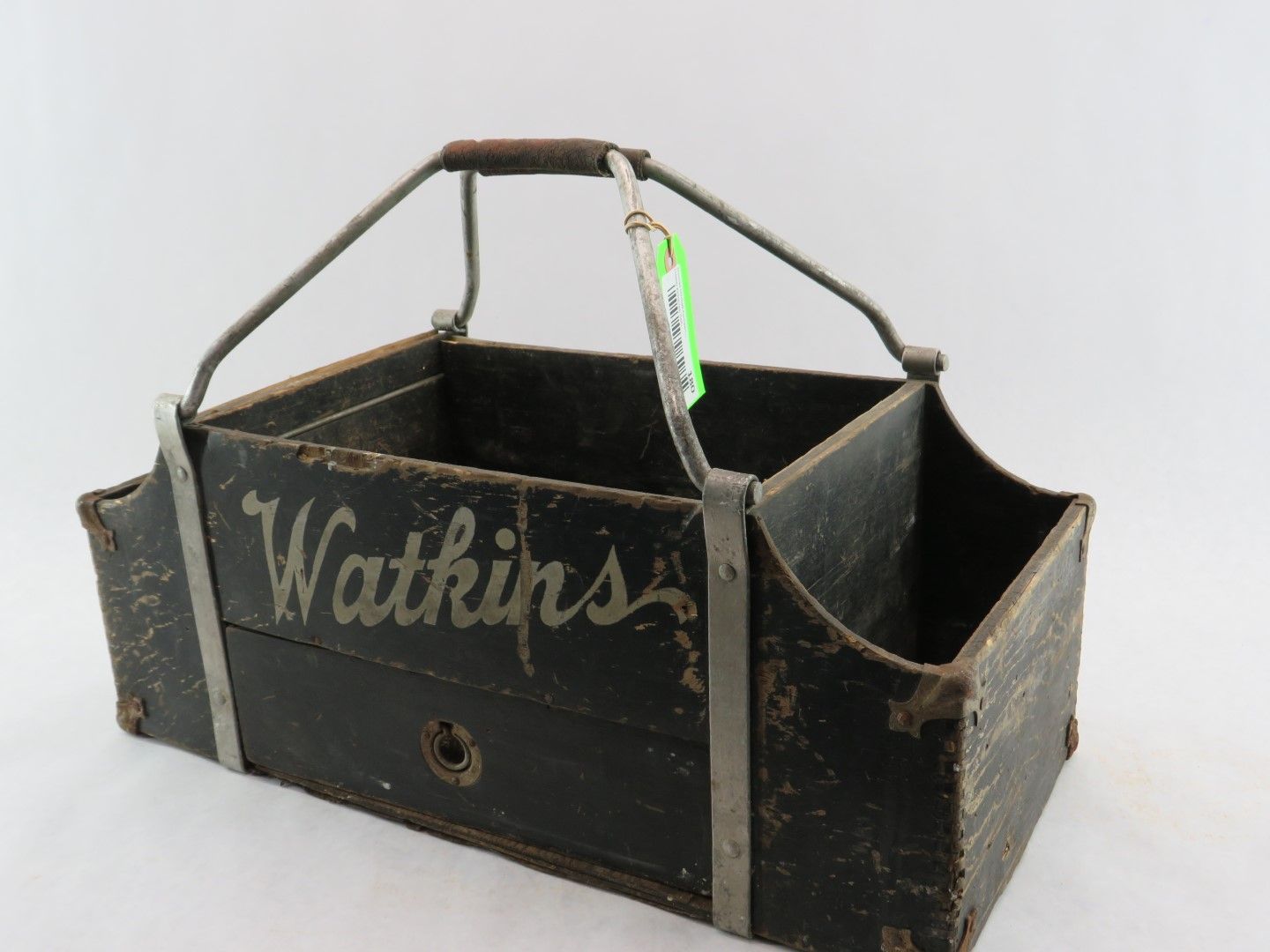 Black Watkins carrier with metal handle, worn wood, holds compartments.