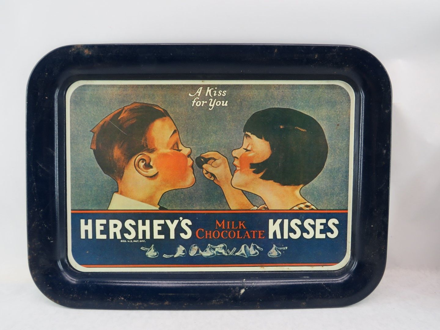 Hershey's Kisses metal tray with vintage couple sharing chocolate. Dark blue border, illustration of a kiss.