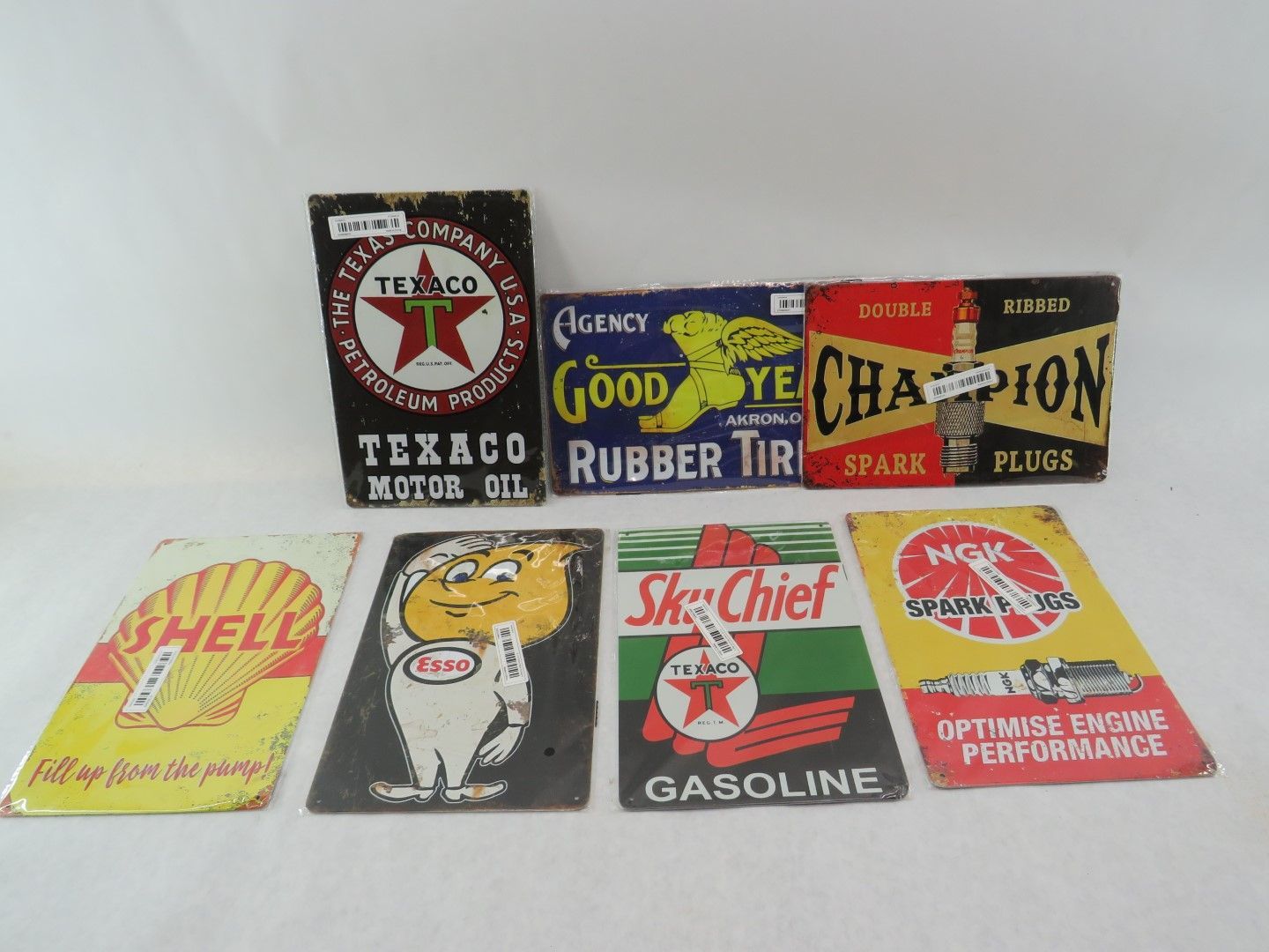 Collection of vintage metal advertising signs for Texaco, Goodyear, Champion, Shell, and more.