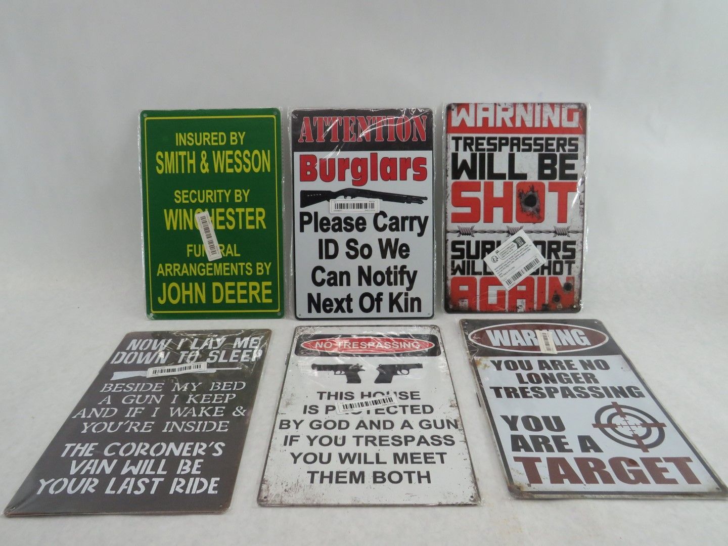 Six warning signs with text, featuring guns, targets, and threats, on a white surface.