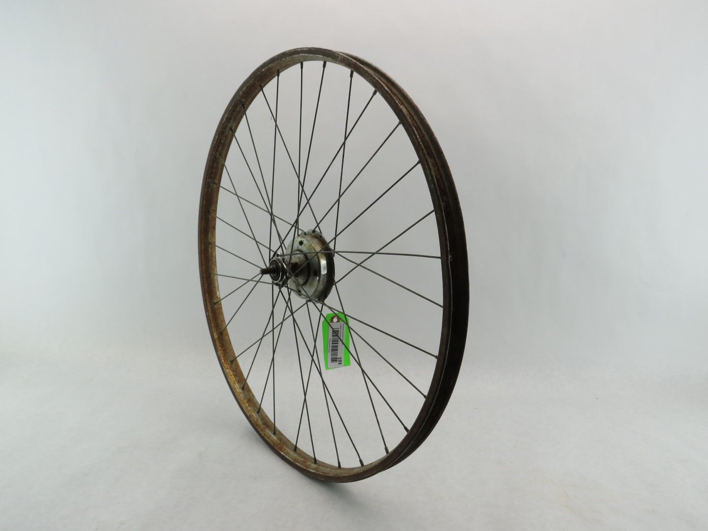 Rusty bicycle wheel with dark spokes and a silver hub, set against a plain white background.
