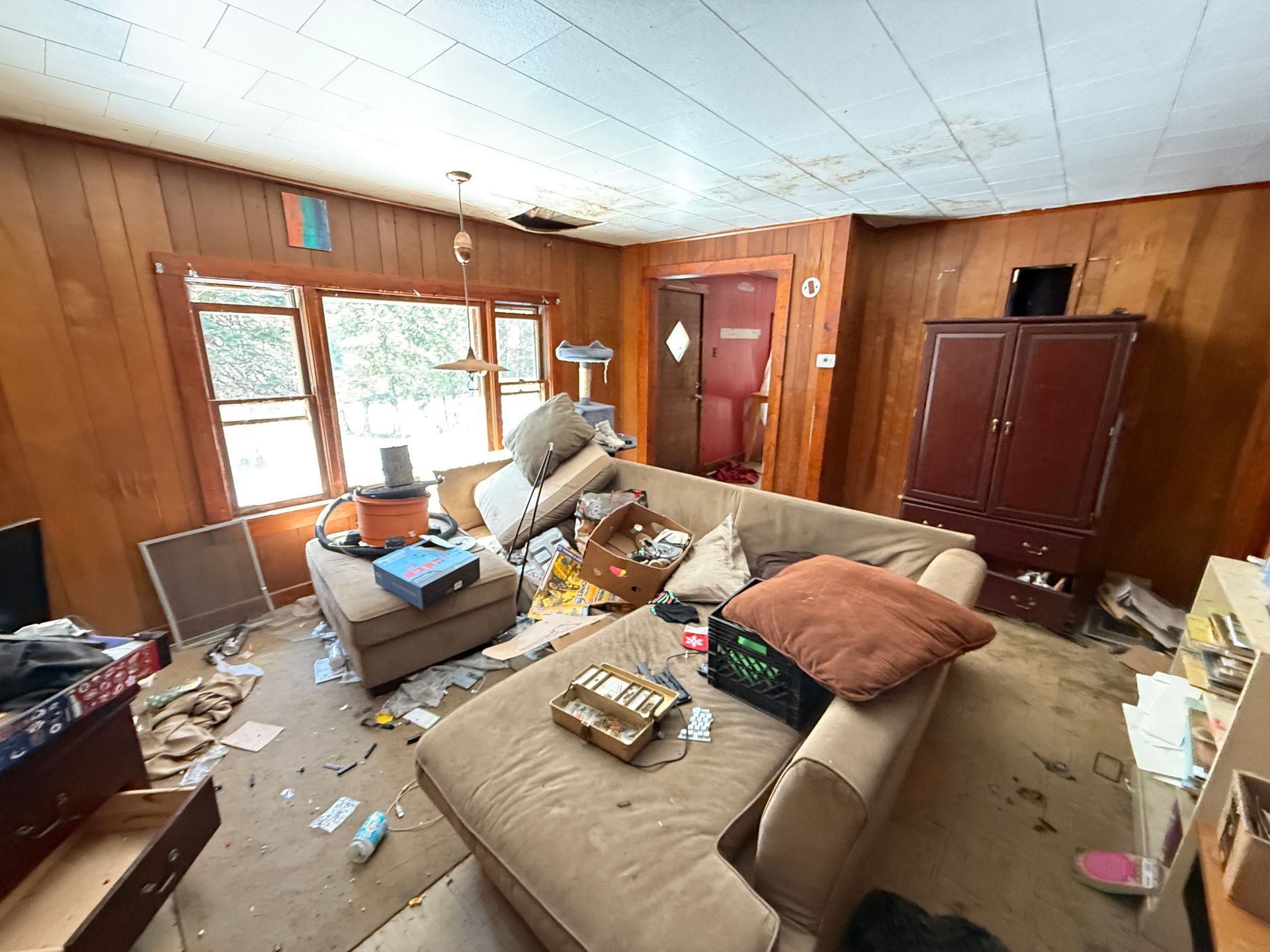 A living room with wood-paneled walls, a large sofa, a brown armoire.