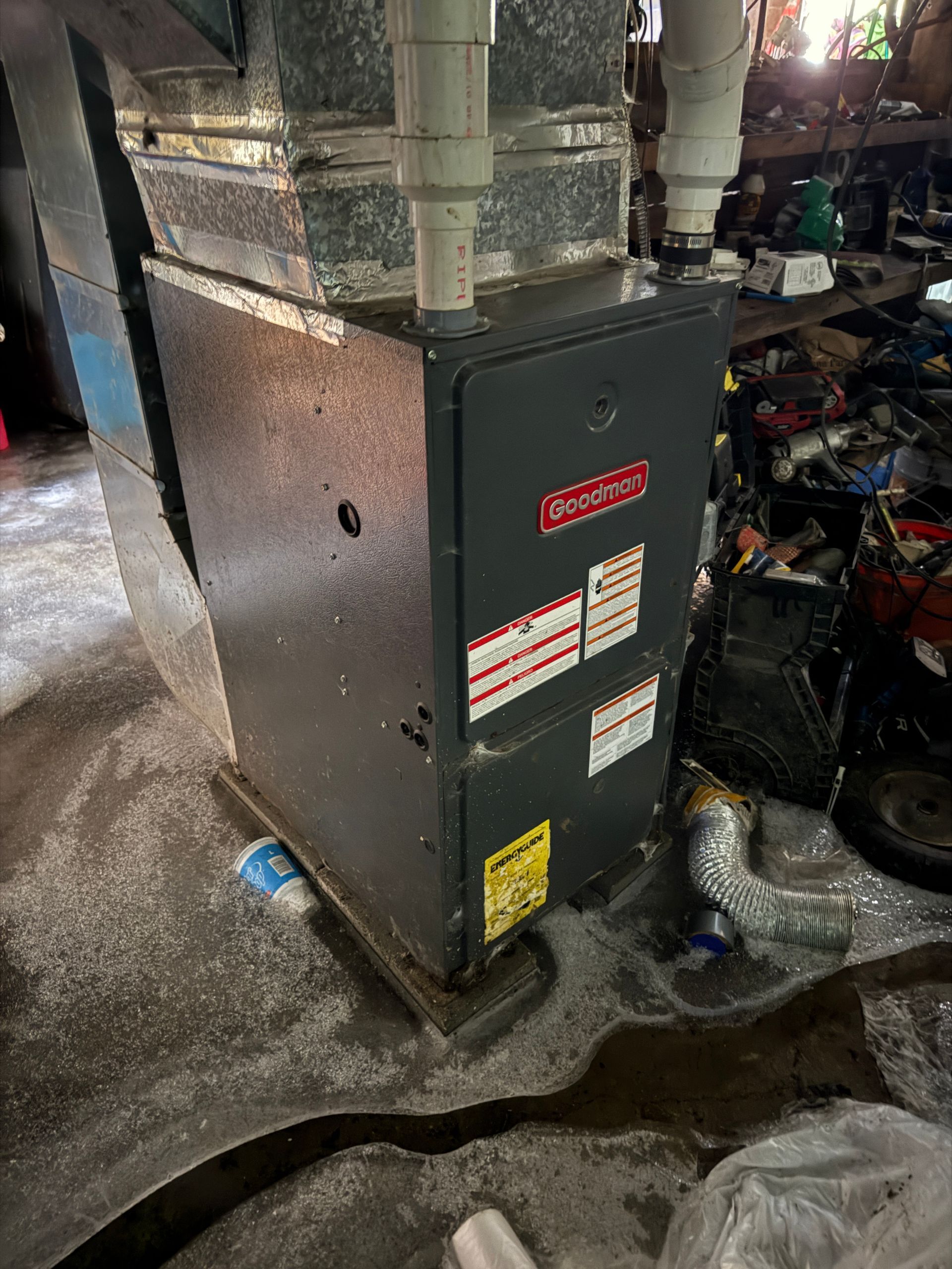 A dark gray furnace sits on a concrete floor in a basement.