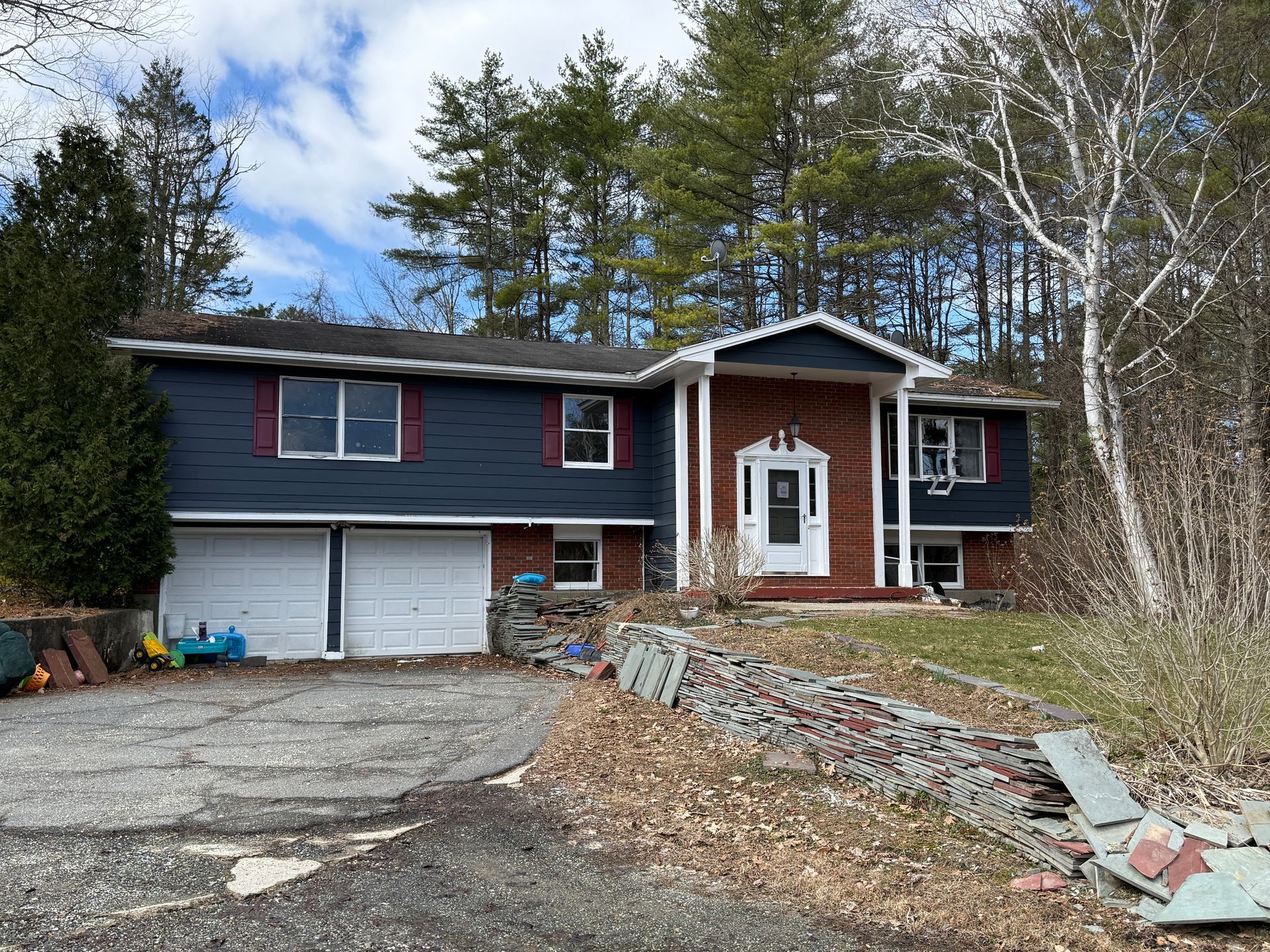 Blue house with red trim, brick entrance, two-car garage.