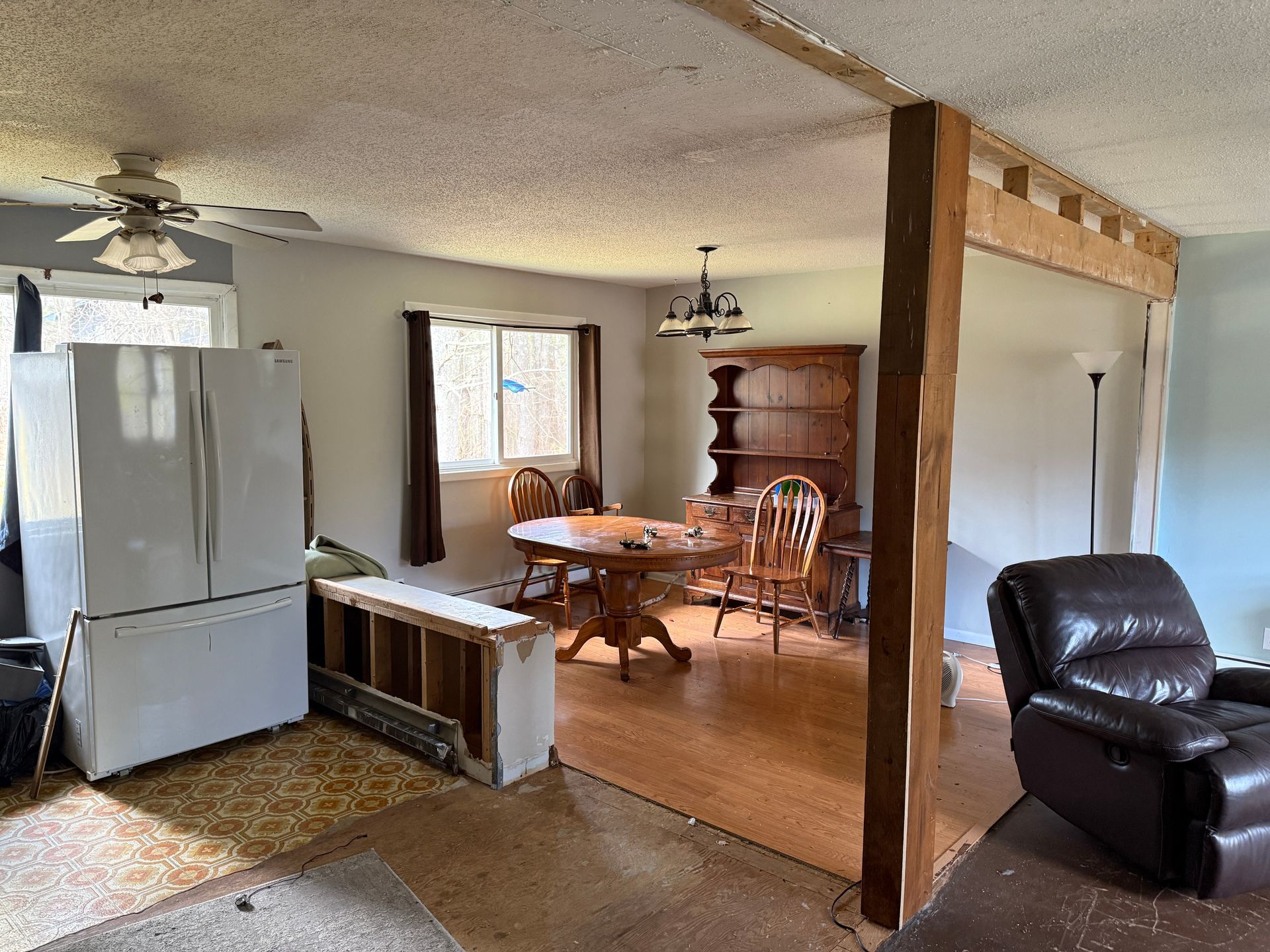 Exposed beams, kitchen with refrigerator, dining area with table, living room with recliner.