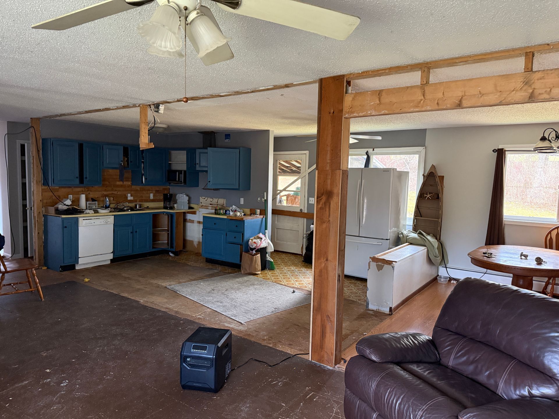 Interior of a house. Blue kitchen cabinets, exposed beams, and a brown leather recliner.
