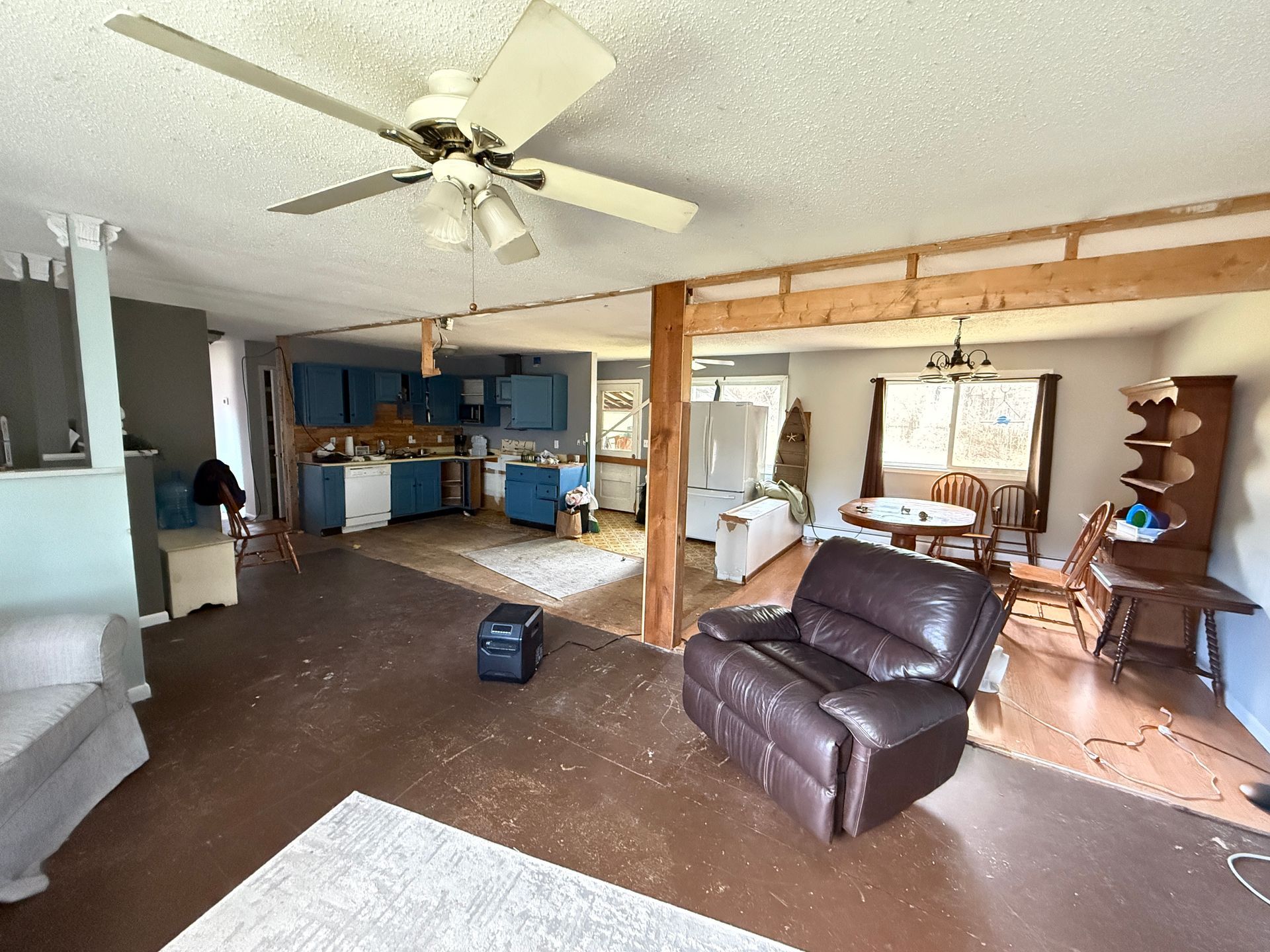 Interior of a room with exposed wooden beams, blue cabinets, and a recliner.