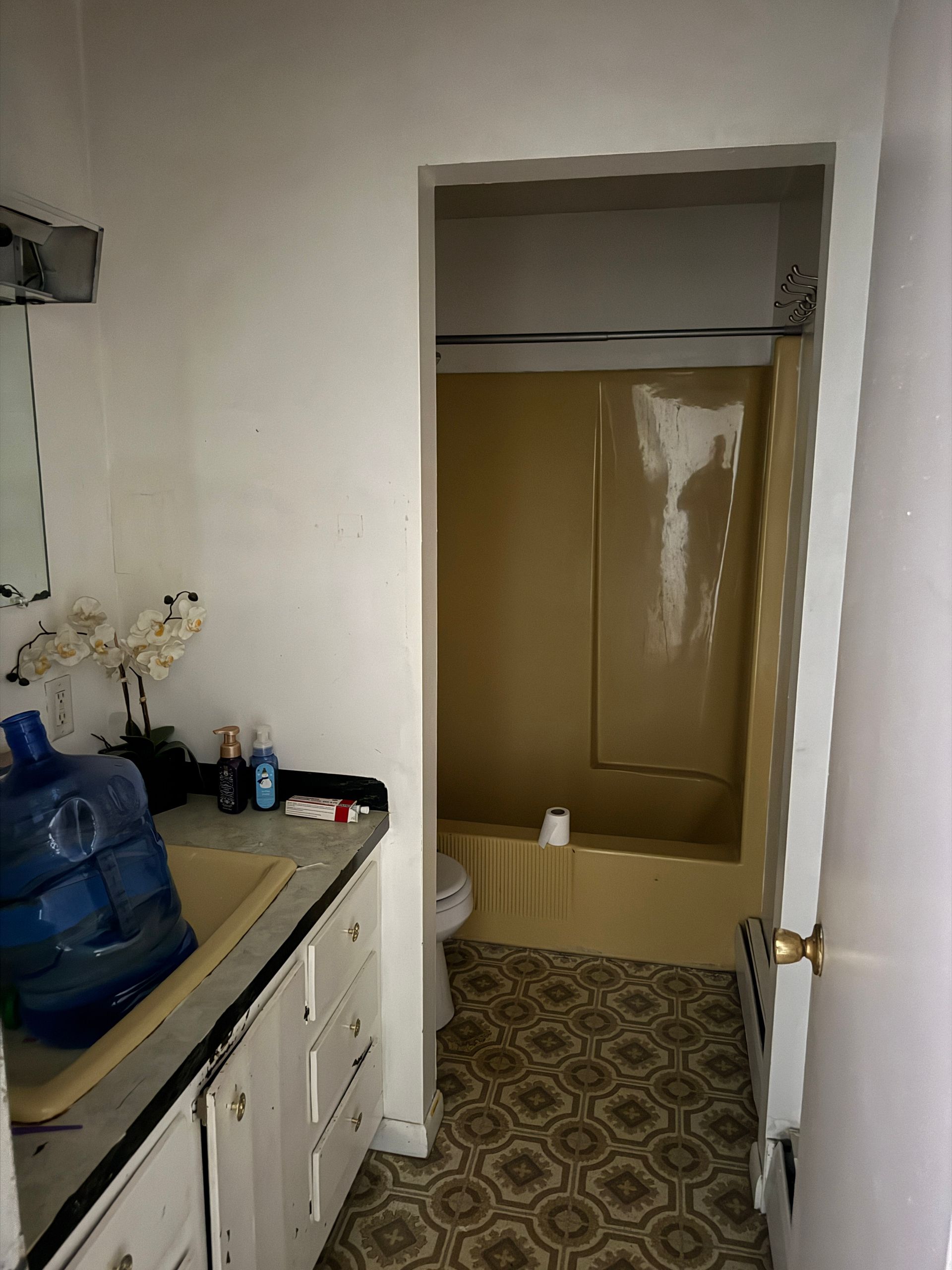Bathroom with yellow tub/shower and vanity.