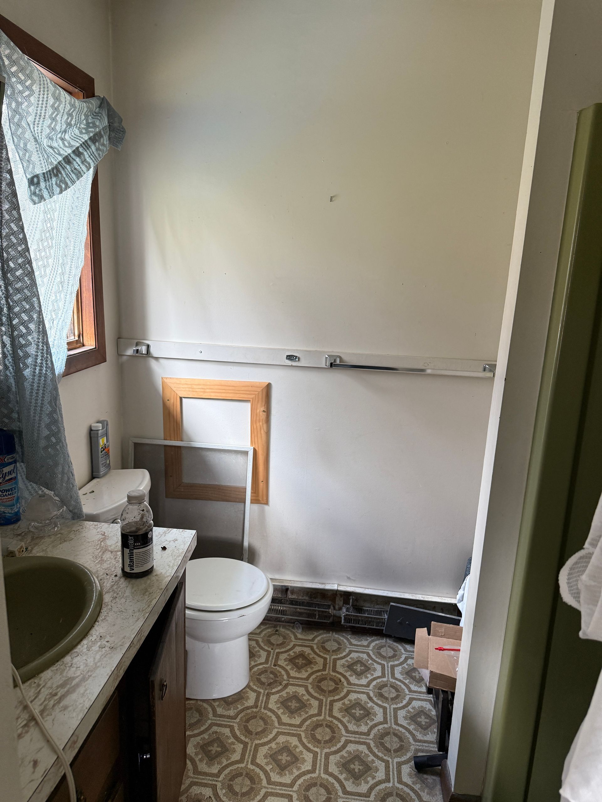 Bathroom with a toilet, sink, brown window frame, blue curtain.