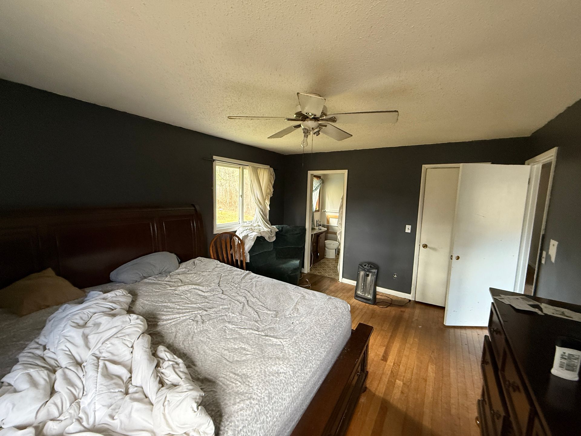 Bedroom with bed, dark walls, and ceiling fan. Doorways lead to bathroom and other room.