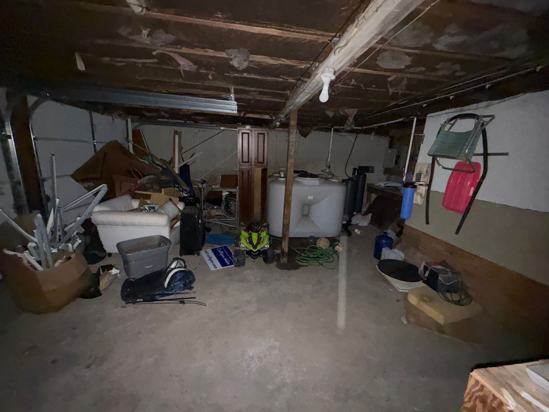 Basement: storage, appliances, exposed beams, bare concrete floor, various objects.