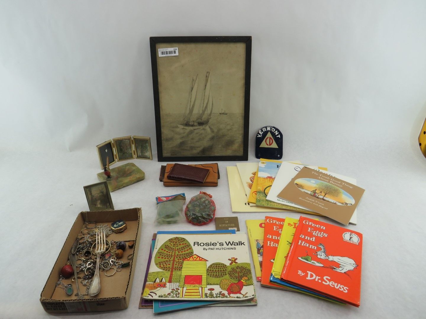 Assorted items: framed art, books, cards, jewelry, and small objects on a white surface.