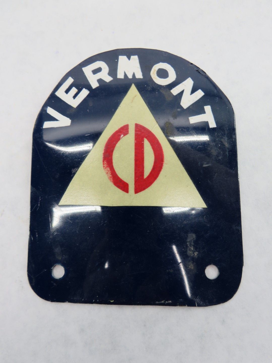 Vermont Civil Defense emblem: dark blue shield with white text, yellow triangle, and red circle with a vertical line.