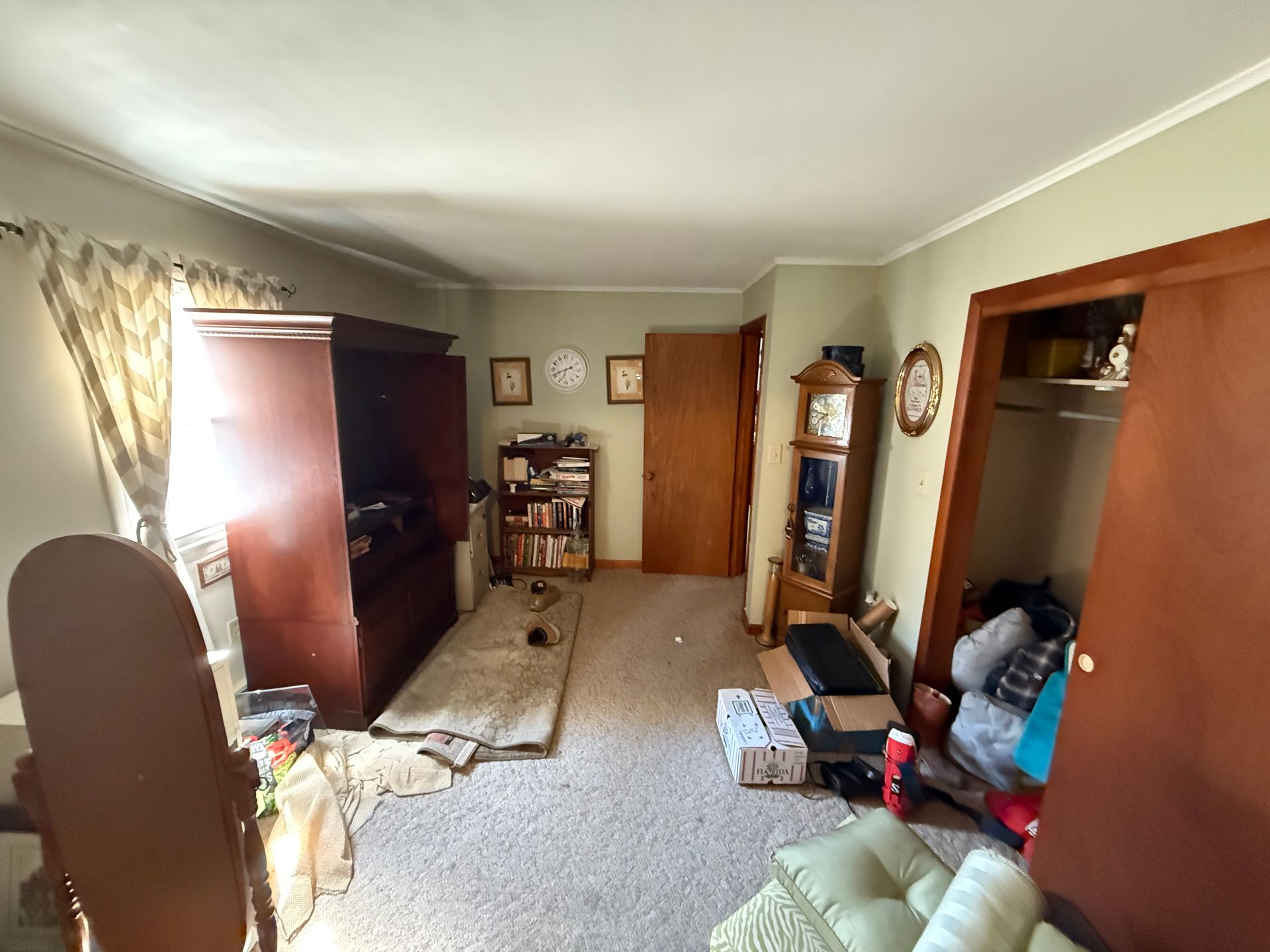 Bedroom with large brown wardrobe and a grandfather clock.