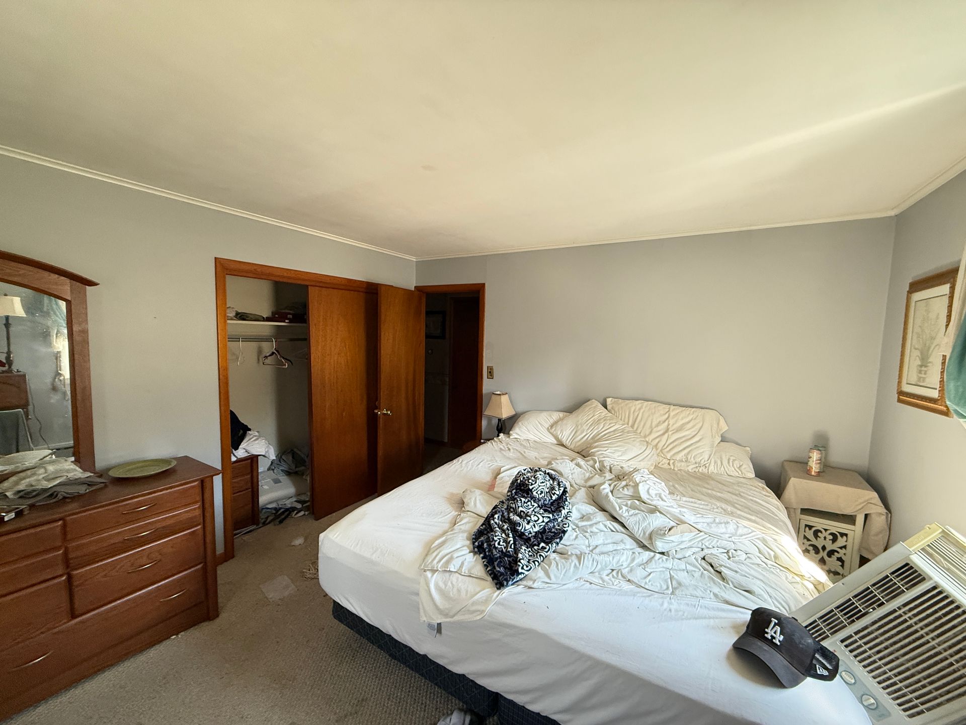 Bedroom with bed, wooden furniture, gray walls, and open closet.