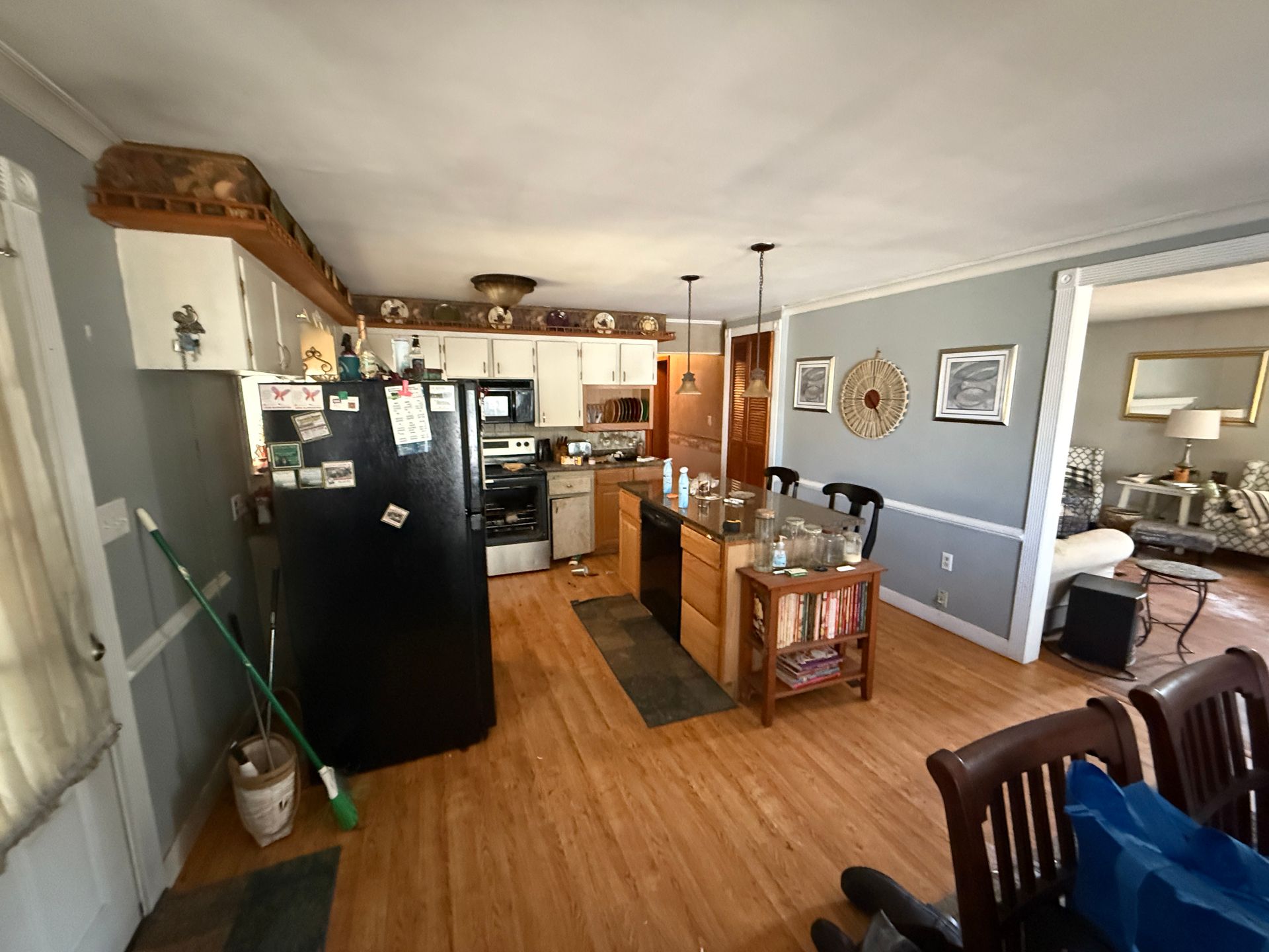 Kitchen with black refrigerator, light wood cabinets, and wooden floors.